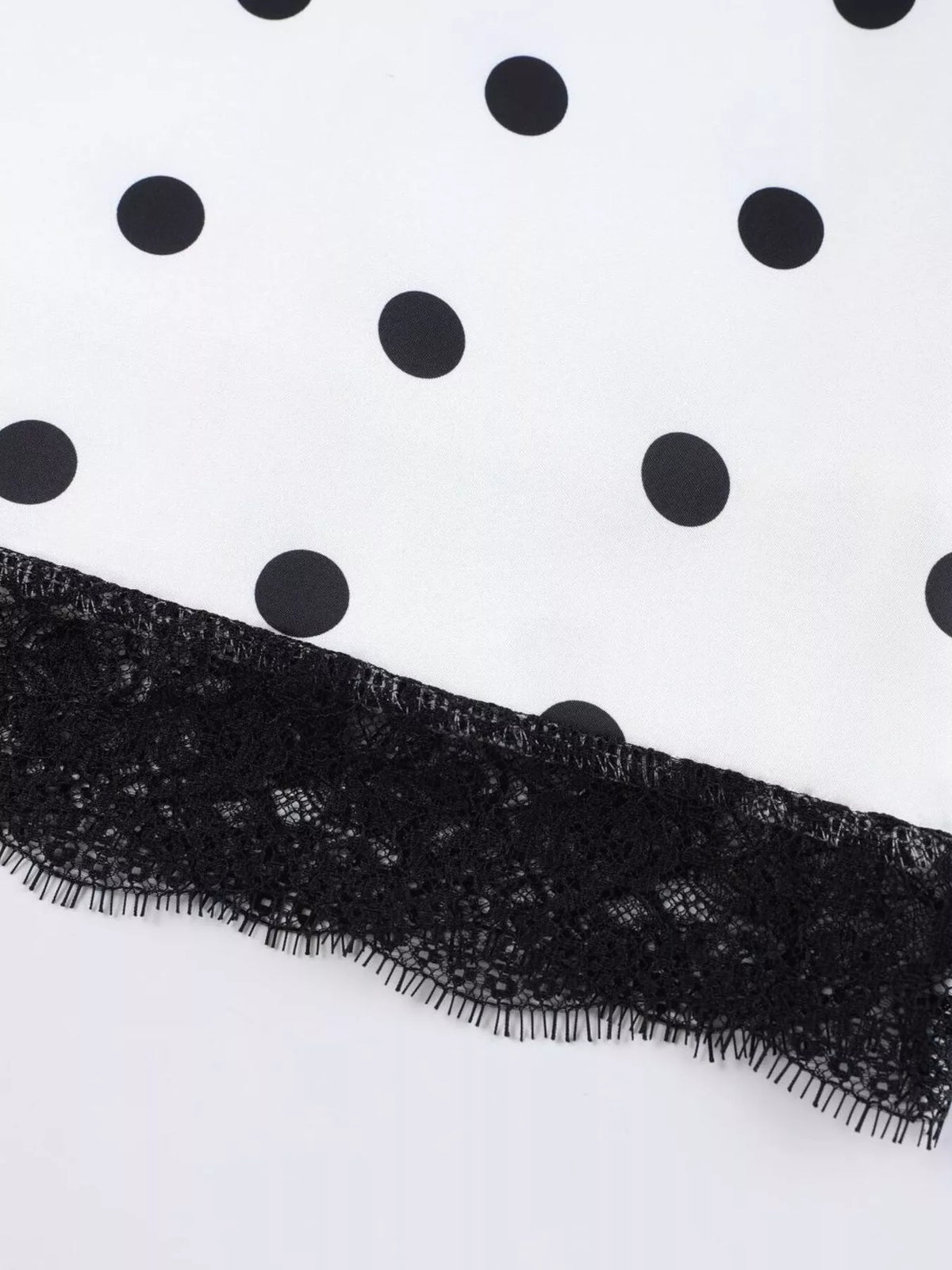 Black floral lace trim along the hem of a white polka dot midi skirt