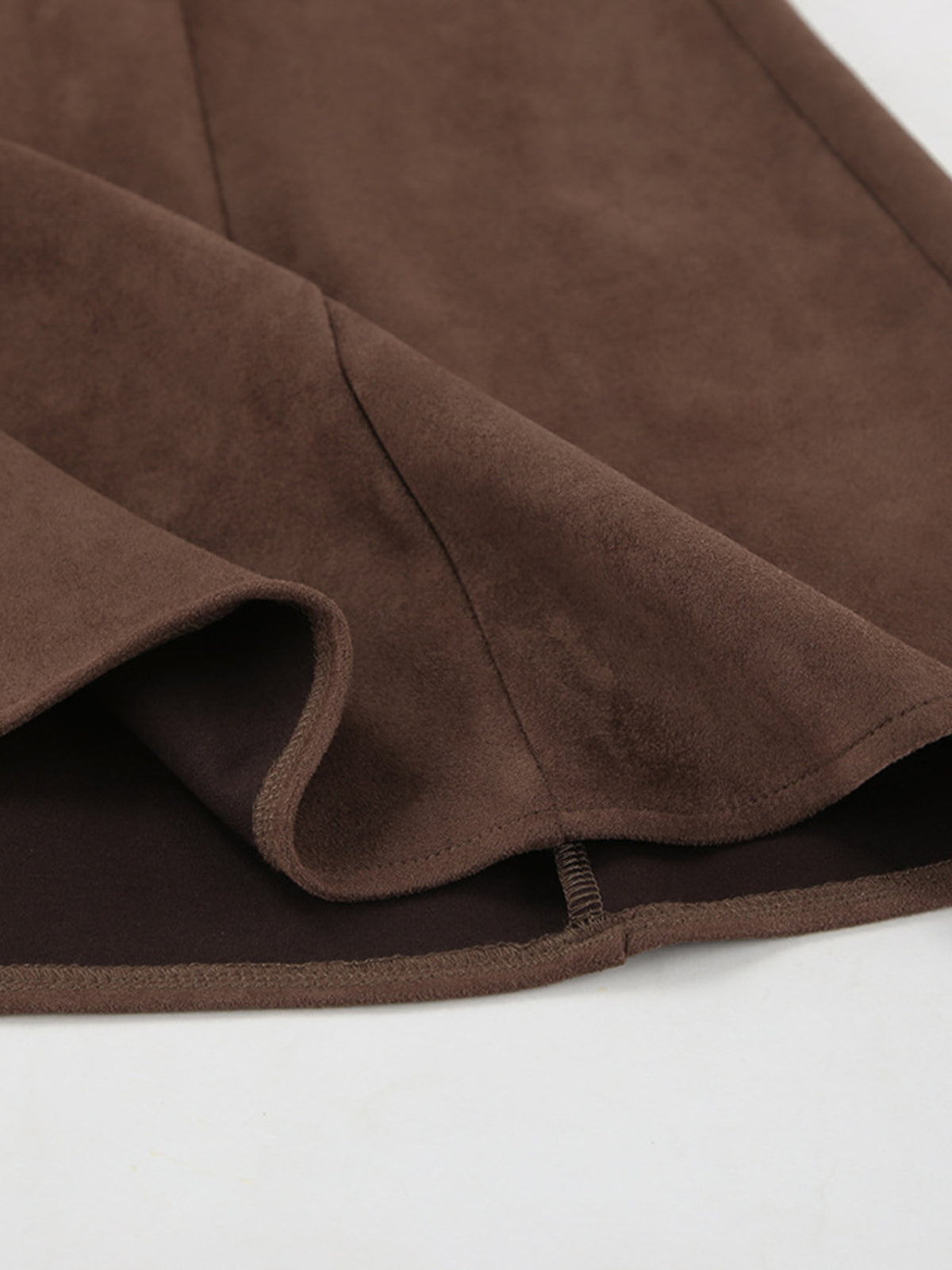 Dark brown suede midi skirt hem with visible seam and soft drape