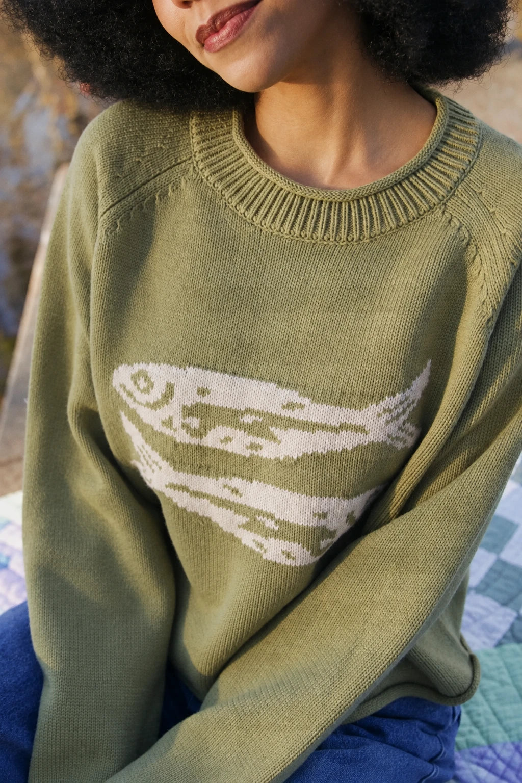 Olive green crewneck sweater with white fish graphic across chest