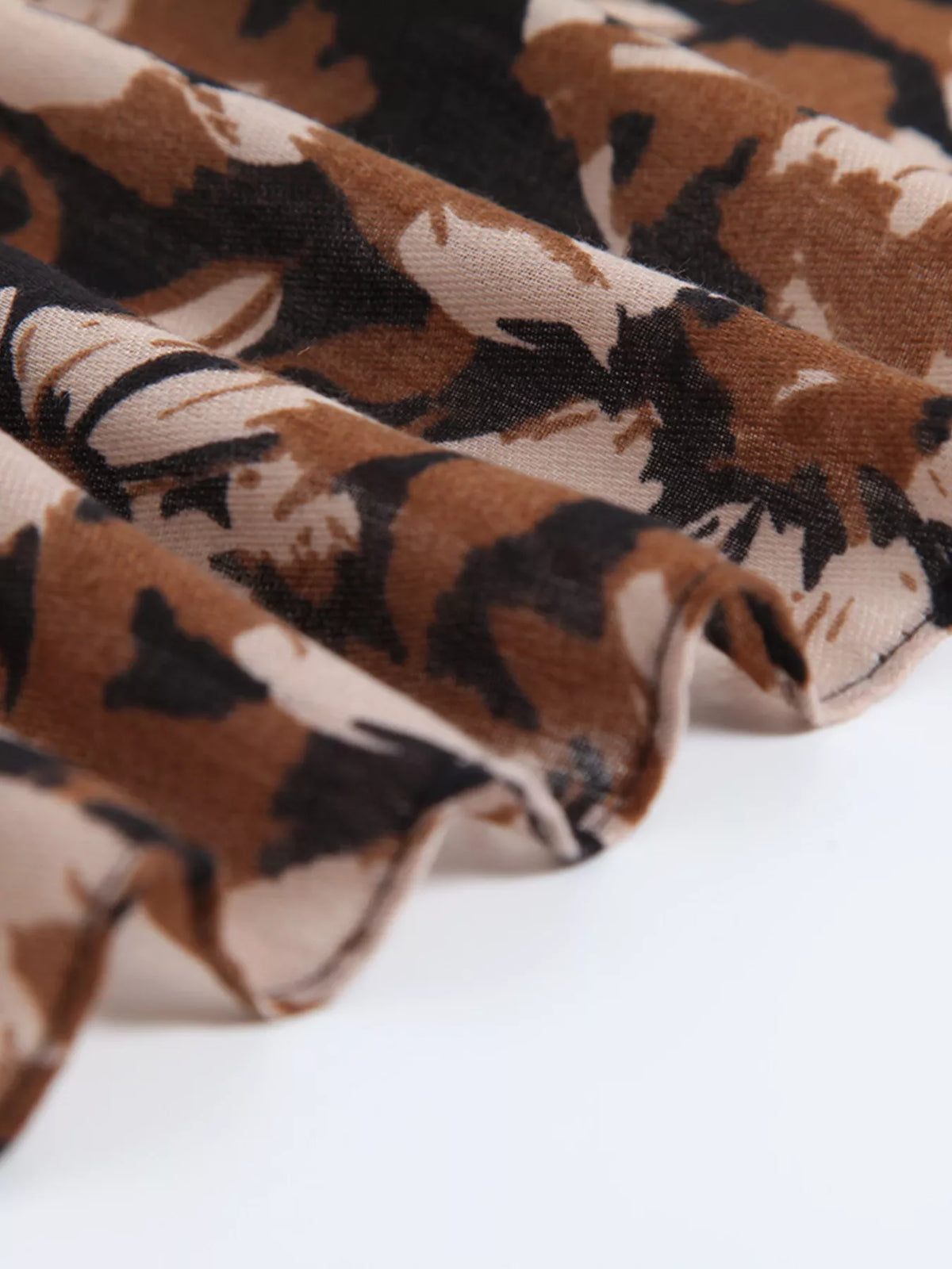 Floral scarf fabric close-up with tan, cream, and dark flower print texture