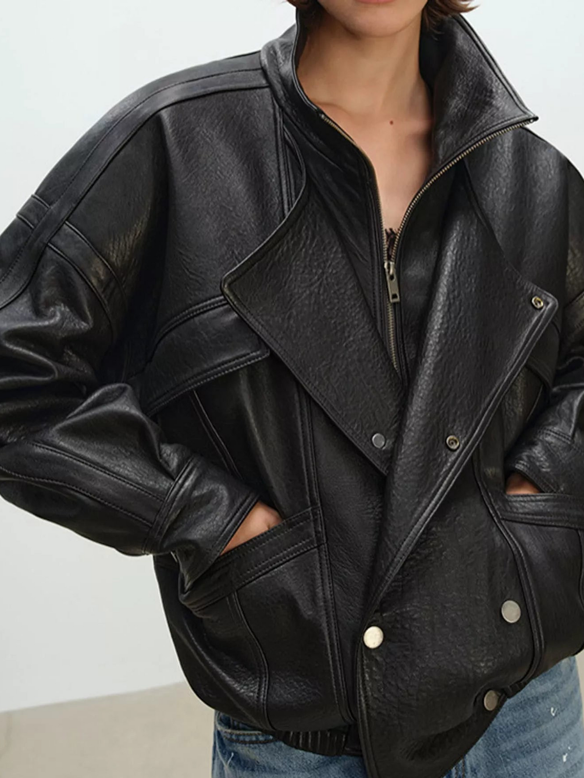 Black leather jacket with zip front and snap-flap pockets, close-up
