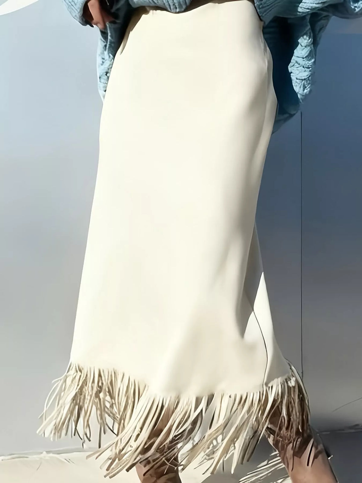 Off-white high-waisted midi skirt with a side slit and fringe hem, worn