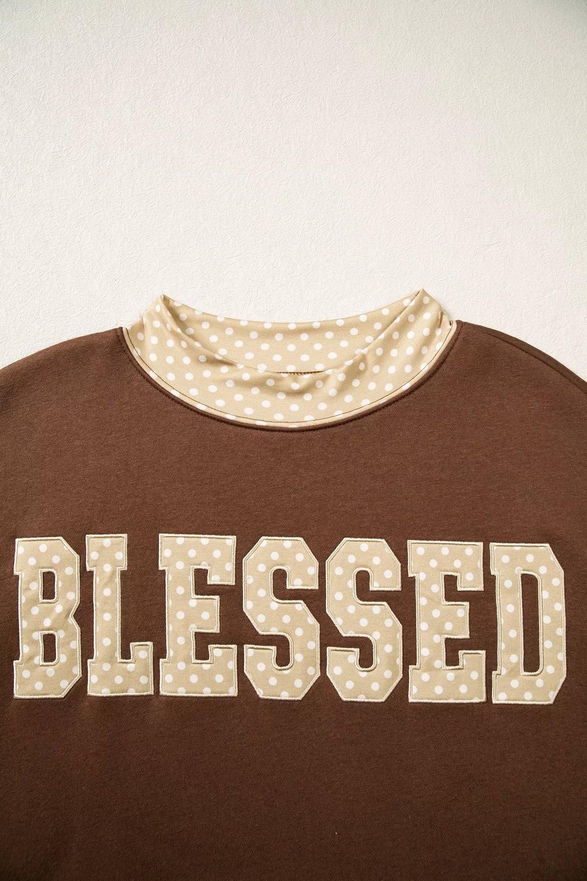Dark brown sweatshirt with polka-dot-trim 'BLESSED' lettering across the chest
