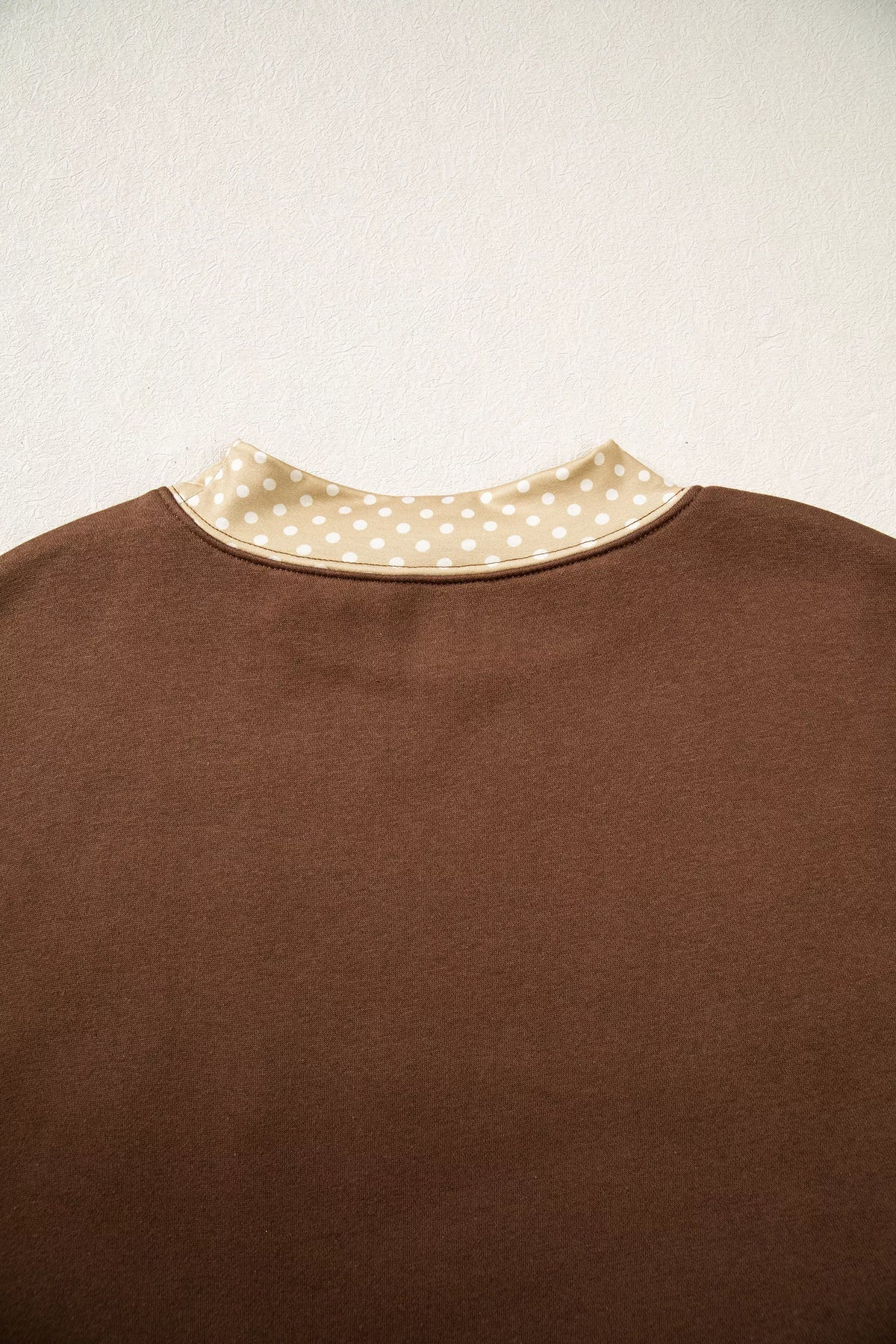 Dark brown high-neck sweatshirt with polka-dot collar band, no visible graphic