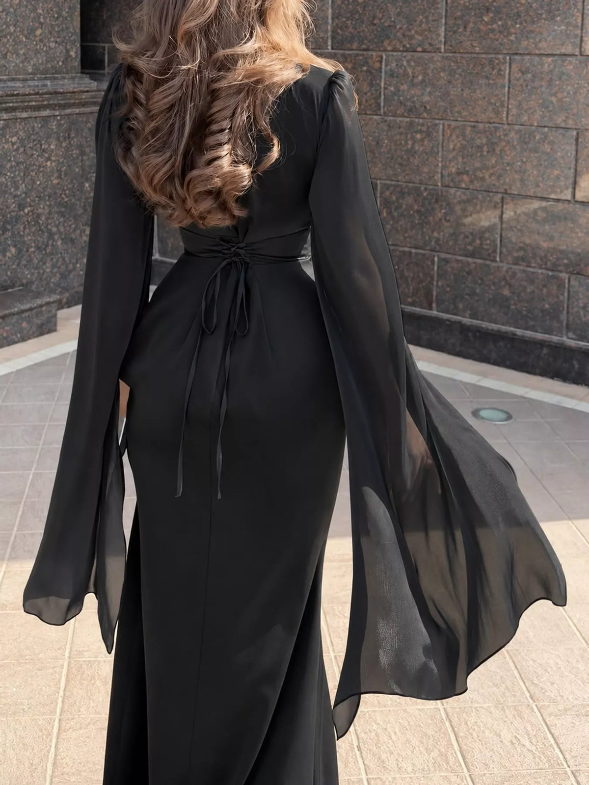 Black maxi dress with a tied back waist and flowing sheer sleeves