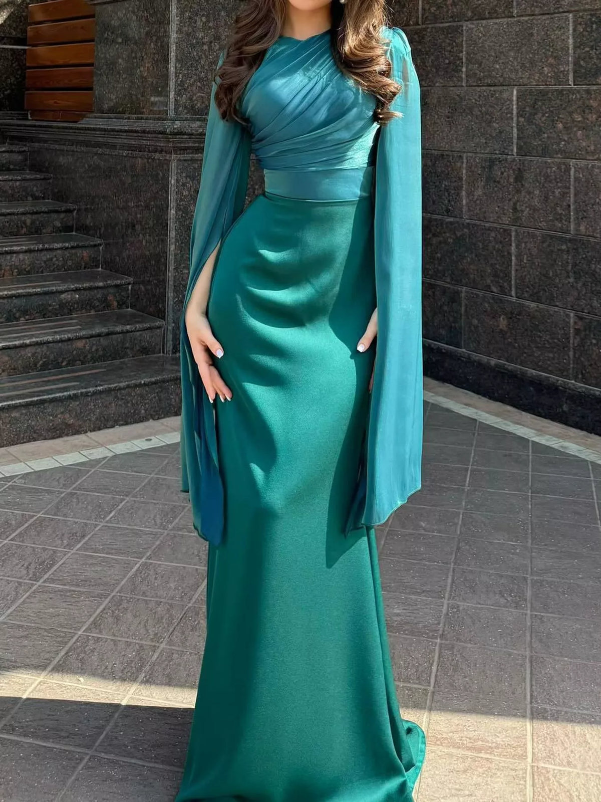 Teal maxi dress showing its fitted silhouette and long draped sleeves
