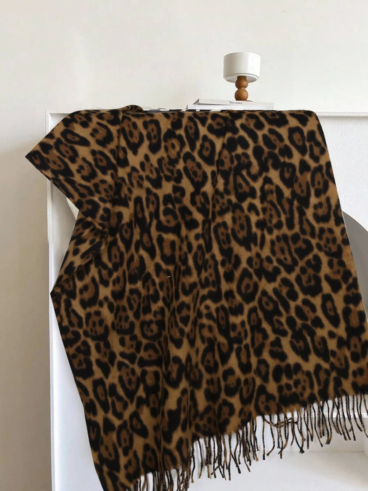 Leopard print scarf with camel-brown base, dark spots, and long fringe ends.