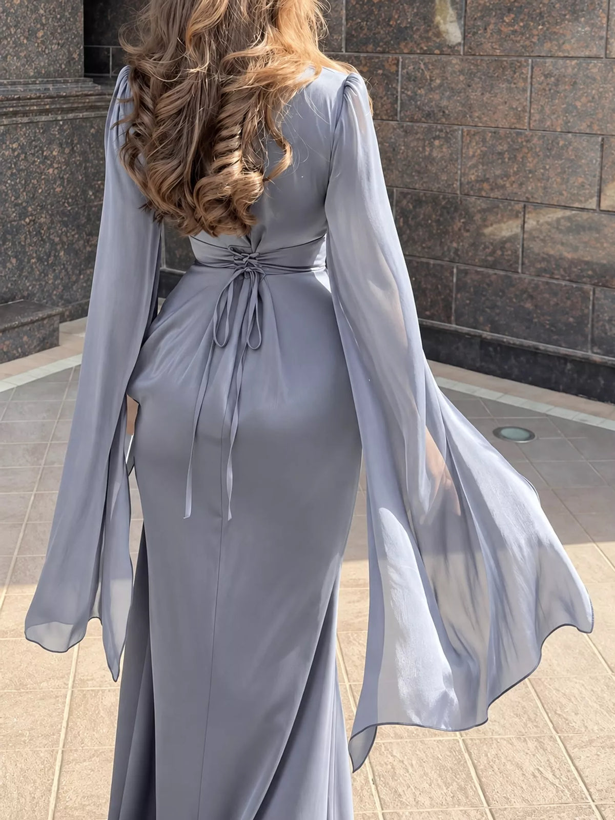 Back view of a gray maxi dress with tie-back waist and sheer flared sleeves