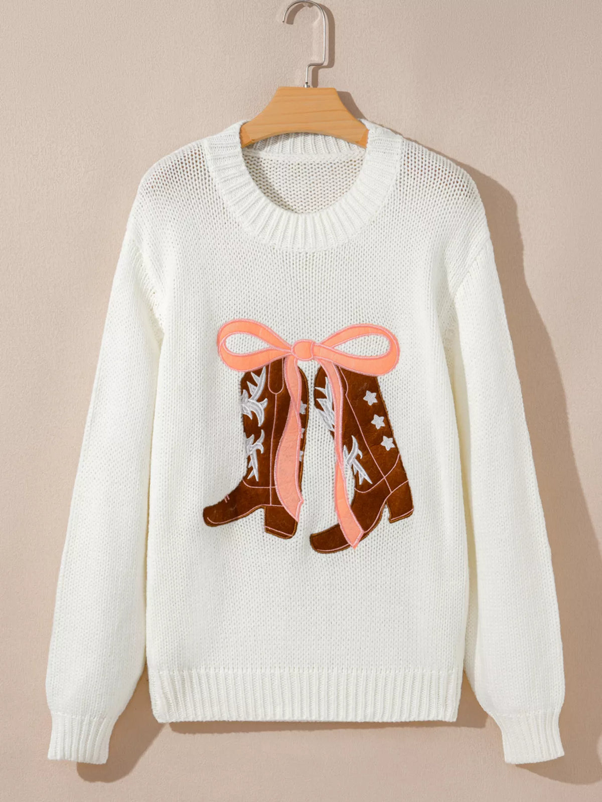 White knit sweater on a hanger with embroidered bow boots graphic
