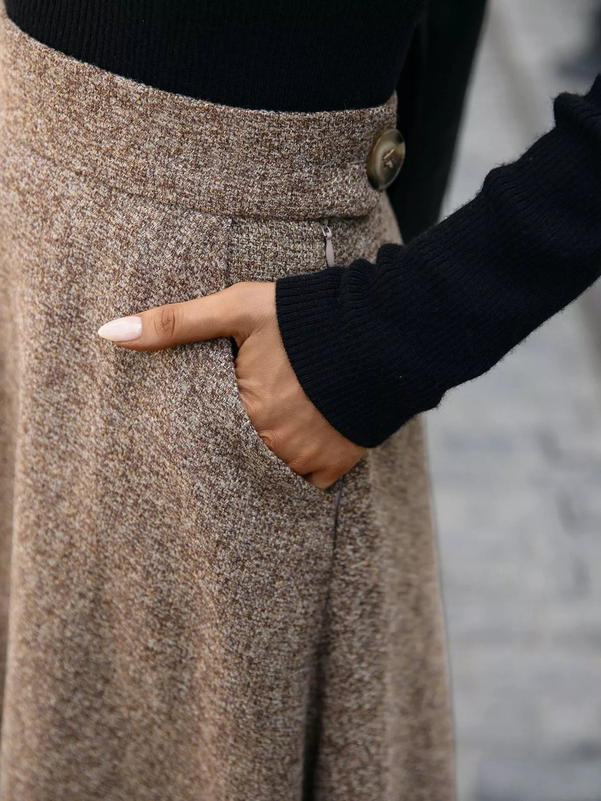 Close-up of brown skirt's textured fabric, waistband, button, and side pocket