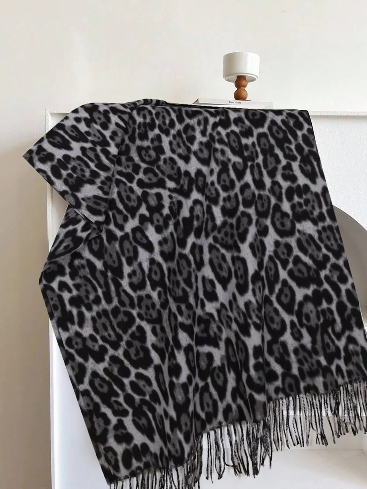 Leopard print fringe scarf in dark gray-black with lighter spots and long fringe.