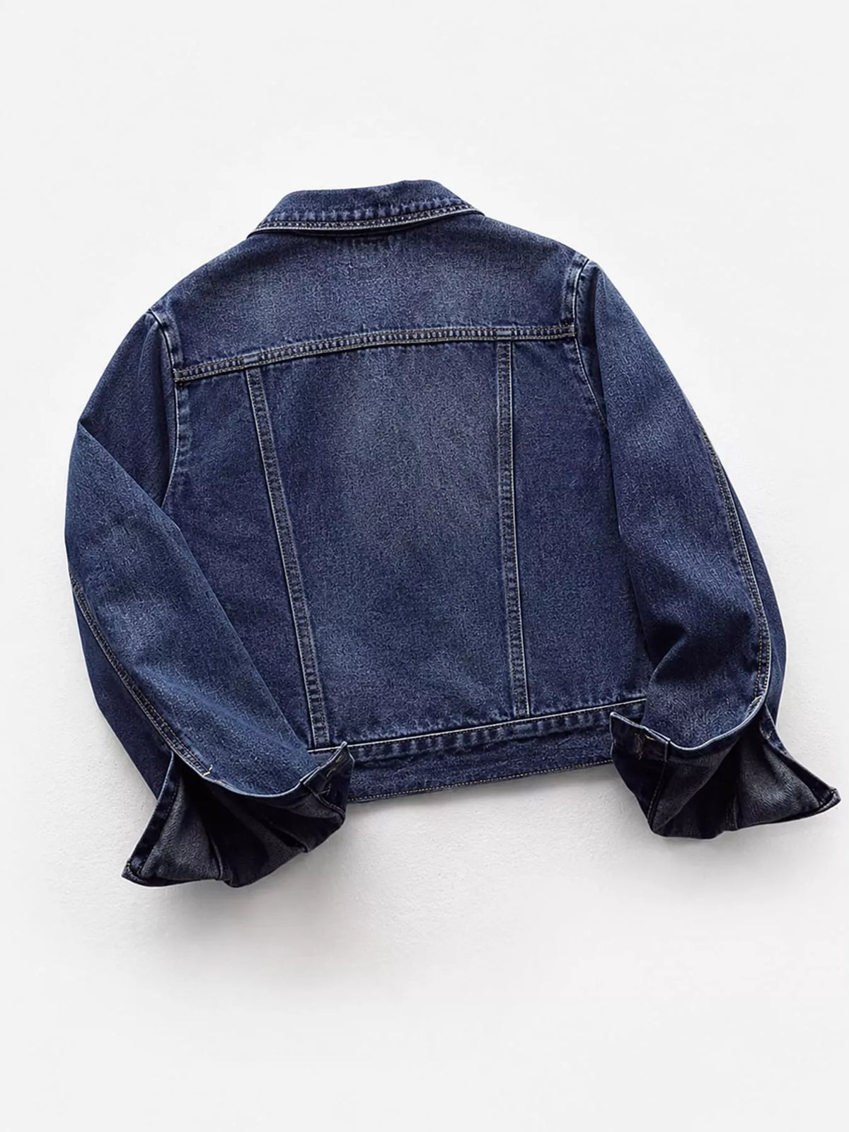 Dark wash denim jacket back view with yoke seams and two-button hem tabs