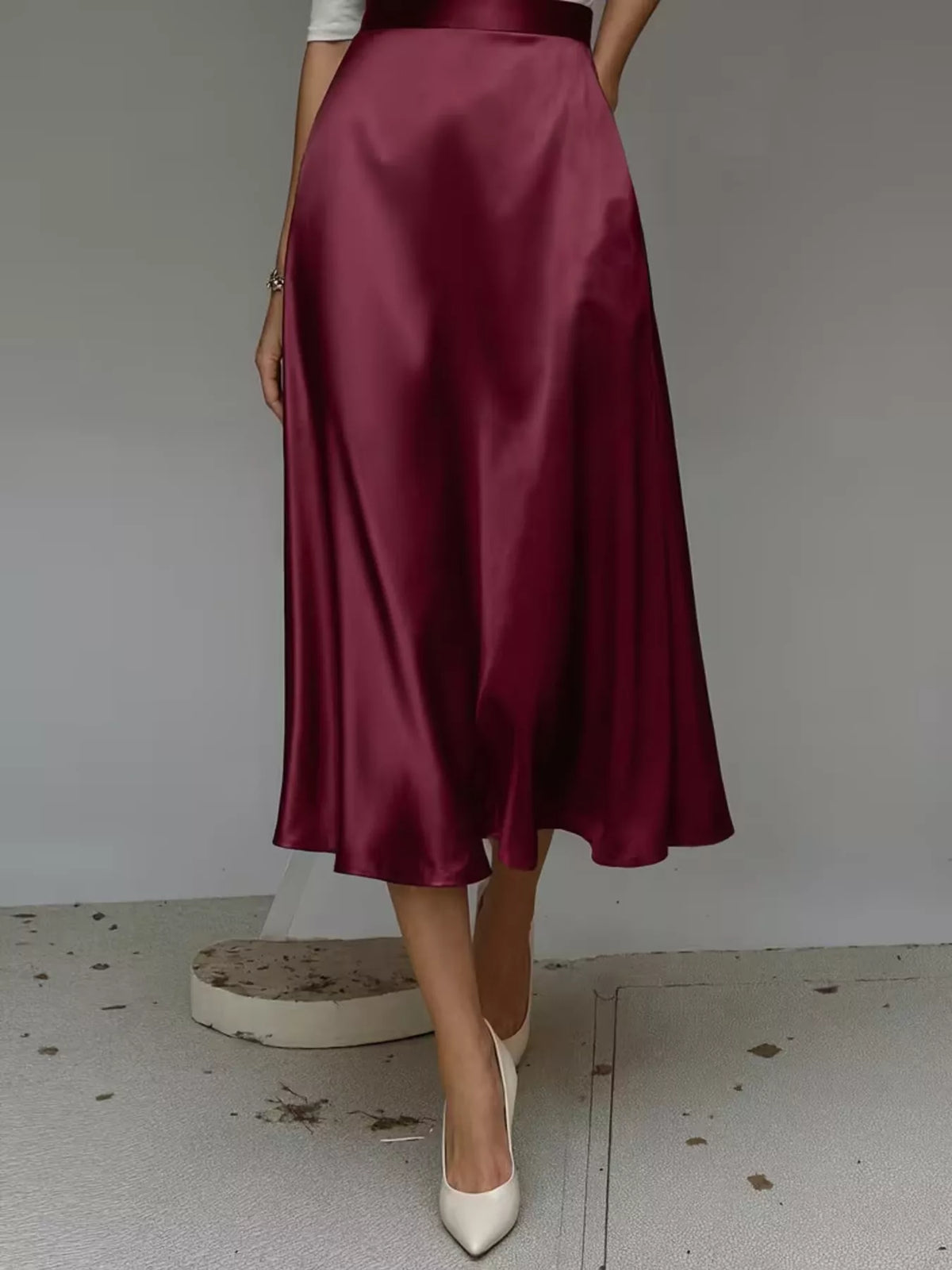 Wine red satin midi skirt shown from the back, with a flowing A-line silhouette.
