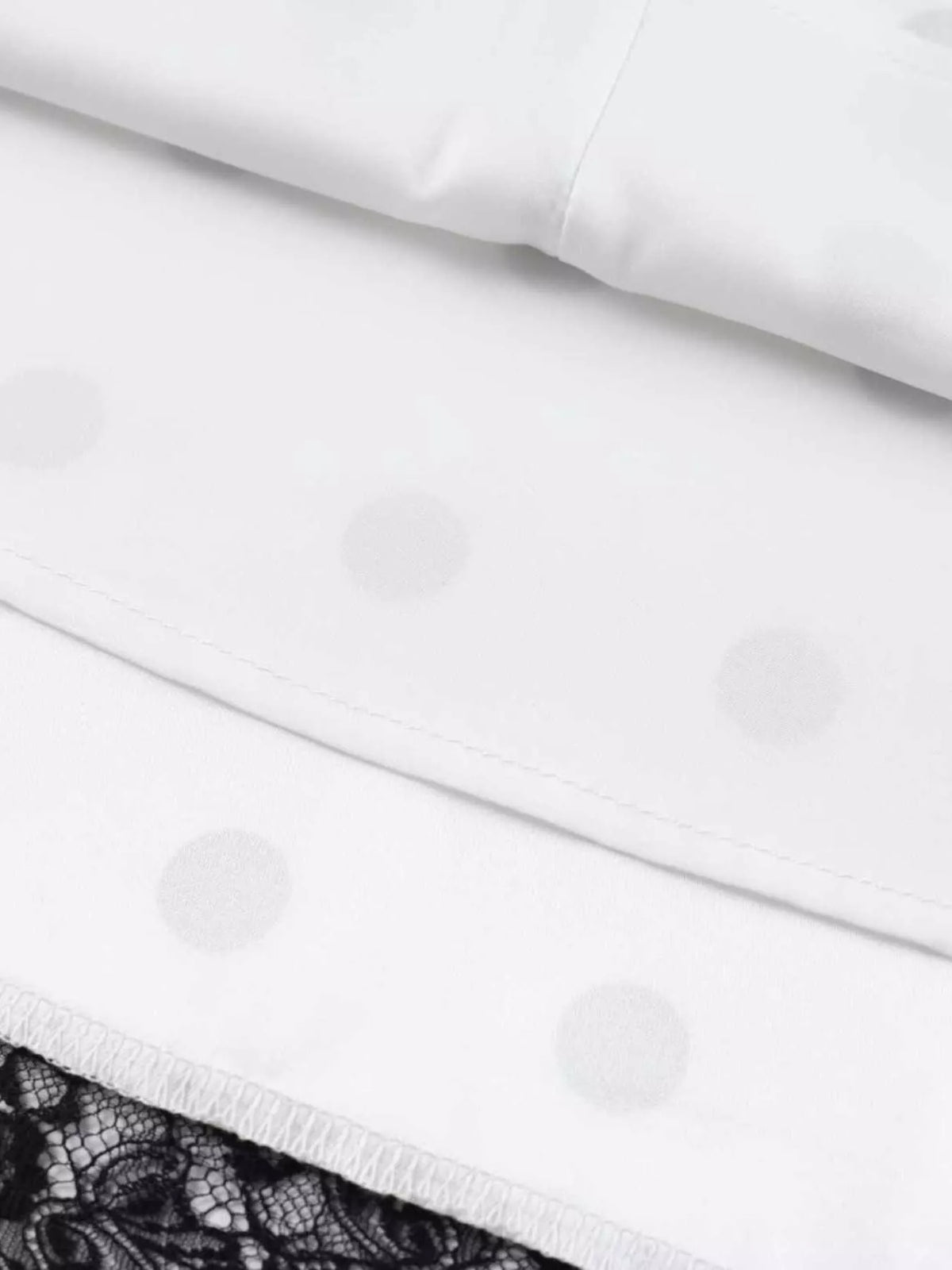 Inside of white polka dot skirt showing the hem seam and black lace trim