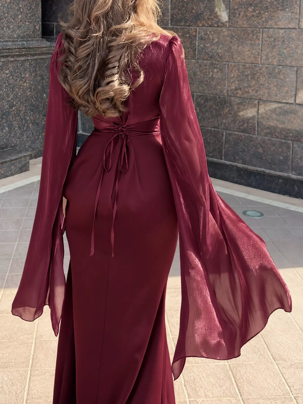 Back of a burgundy maxi dress with a waist tie and sheer split sleeves