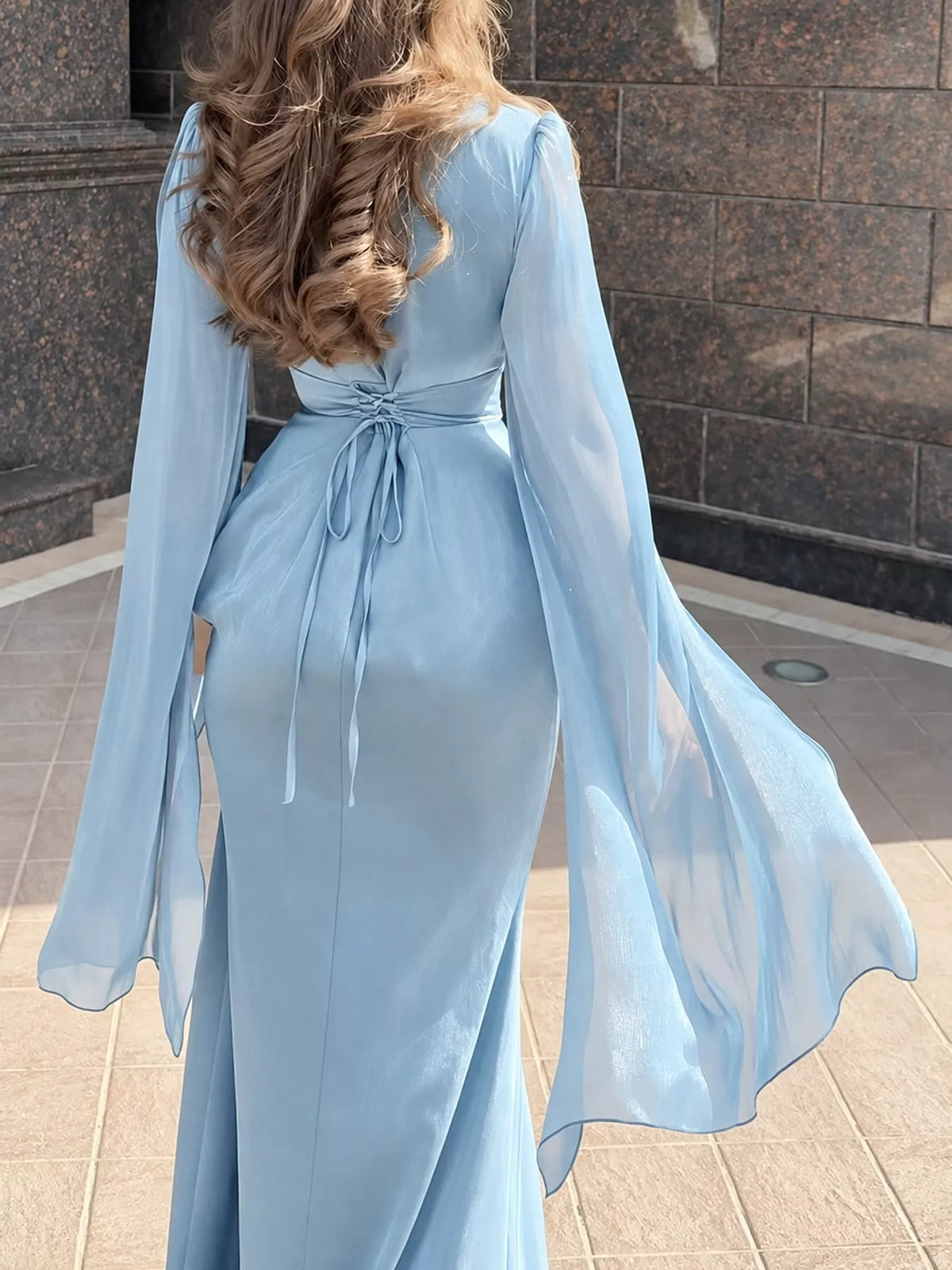 Back of the light blue maxi dress with a waist tie and sheer flared sleeves