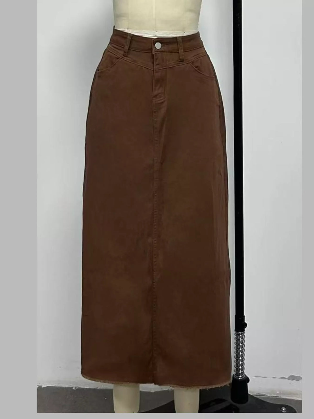 Coffee brown denim maxi skirt on mannequin, long A-line silhouette with stitched center seam.