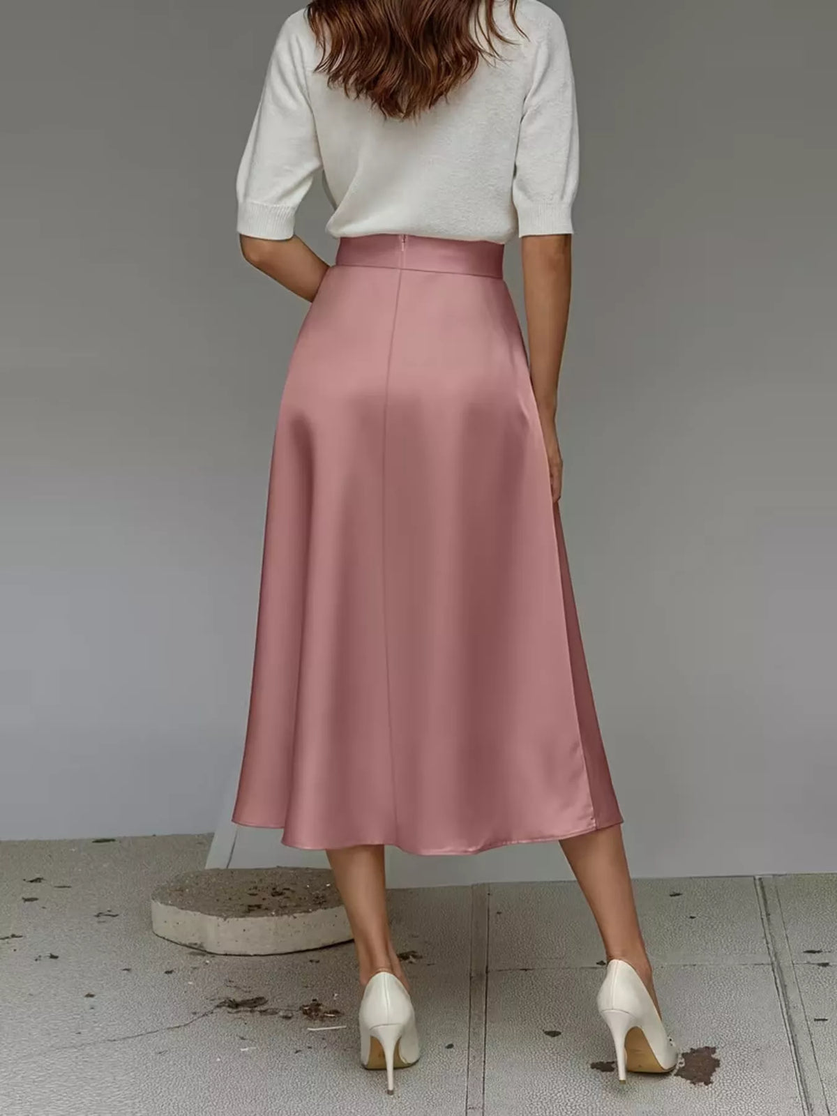 Back view of a pink satin midi skirt with a high waist and flowing A-line silhouette.