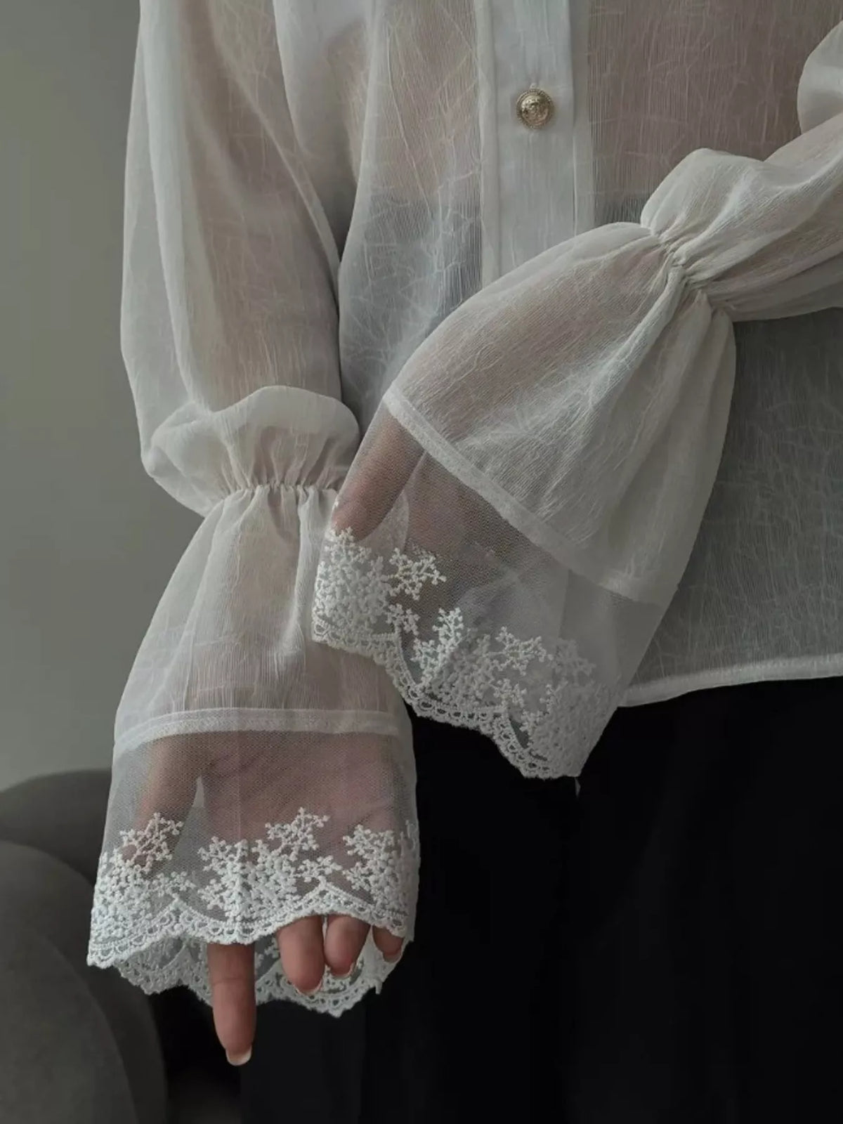 Close-up of sheer flounce sleeves with scalloped floral lace cuffs