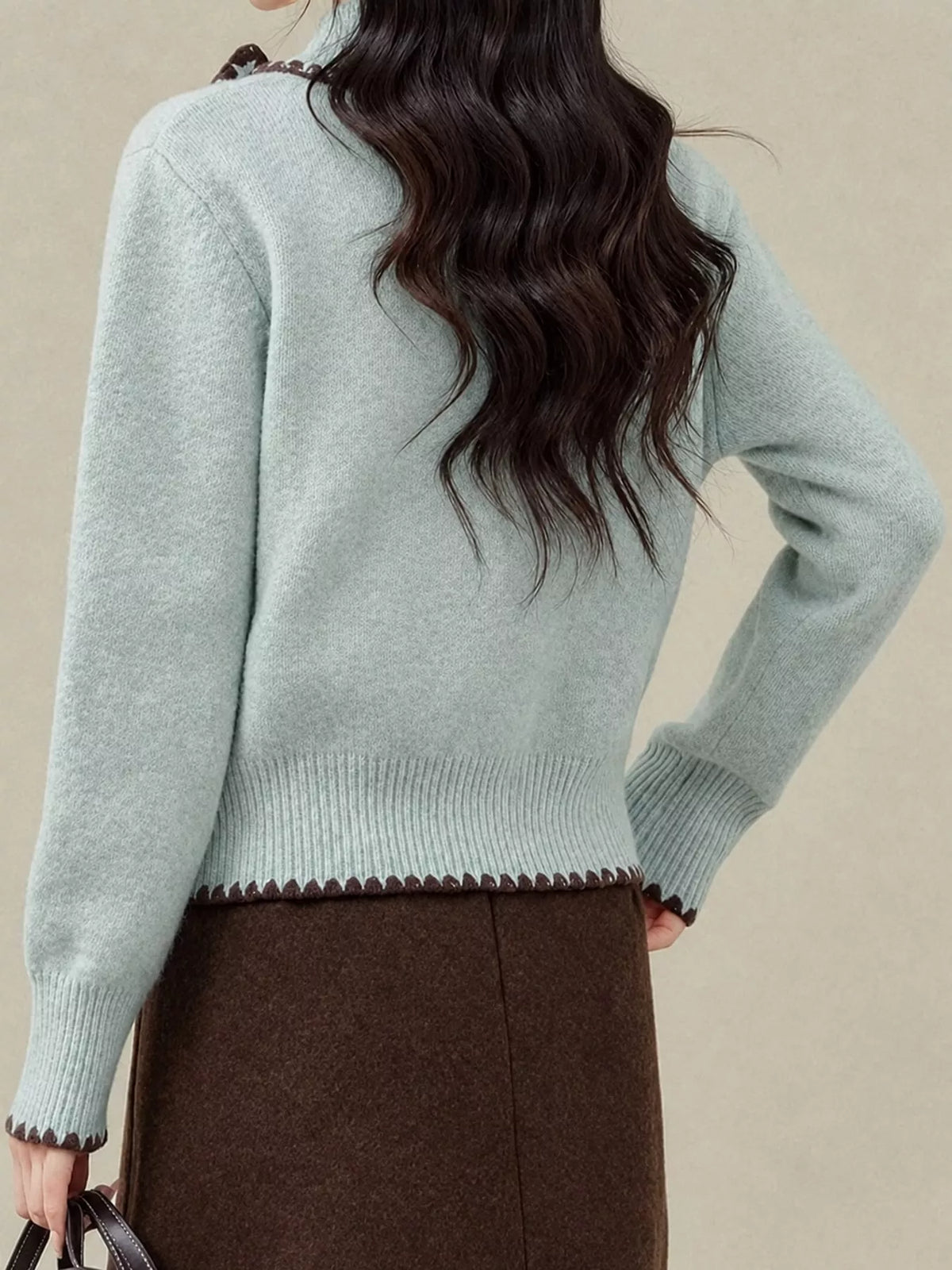 Back of pale blue cardigan with brown contrast trim along the ribbed hem and cuffs