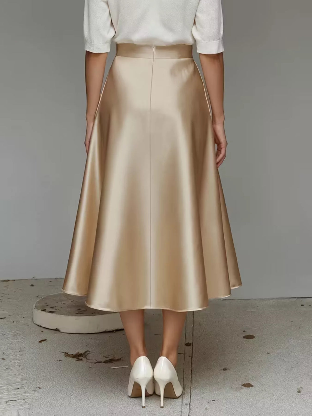 Back view of a champagne satin midi skirt with a flared silhouette