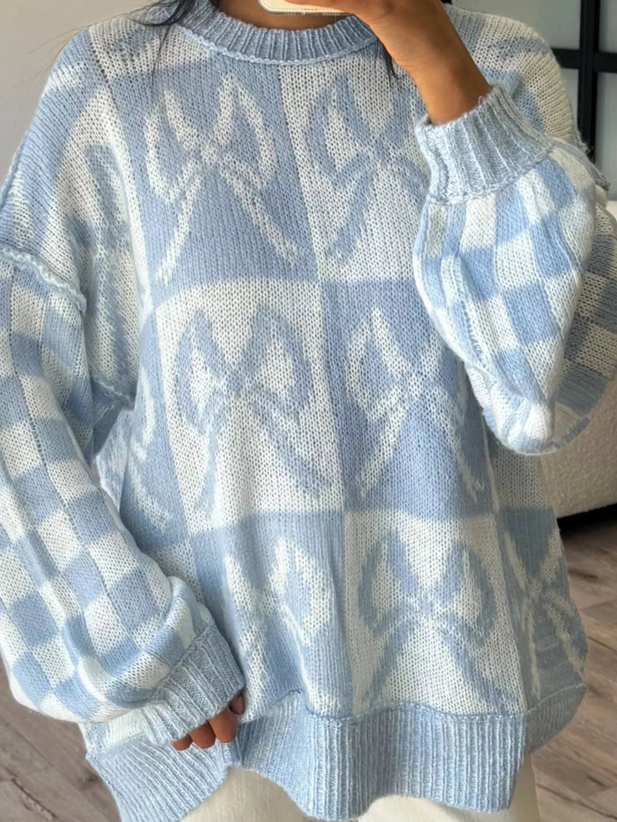 Light blue knit sweater with white checkerboard bow pattern, ribbed crew neck