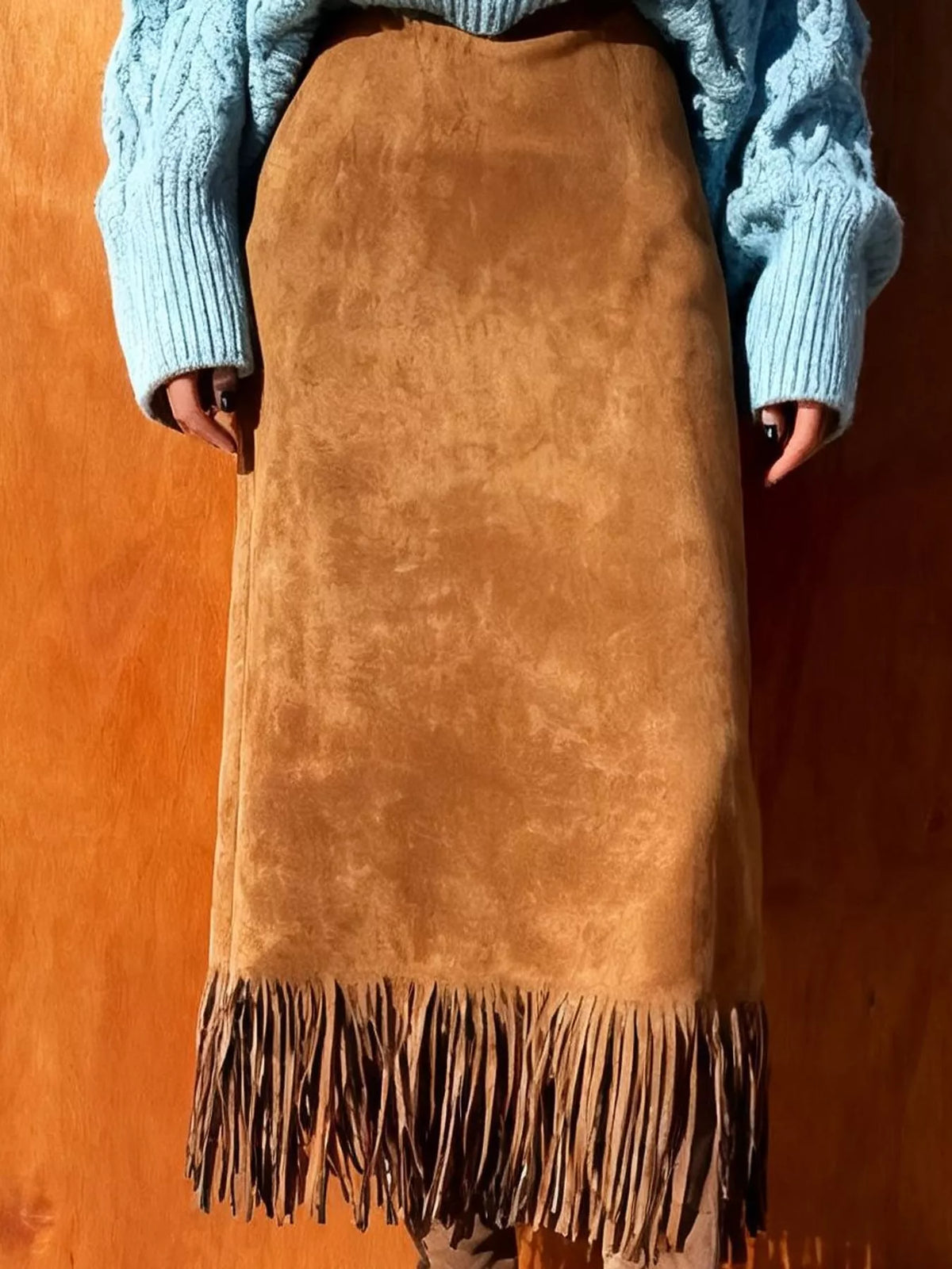Front view of a light brown high-waisted midi skirt with fringe hem