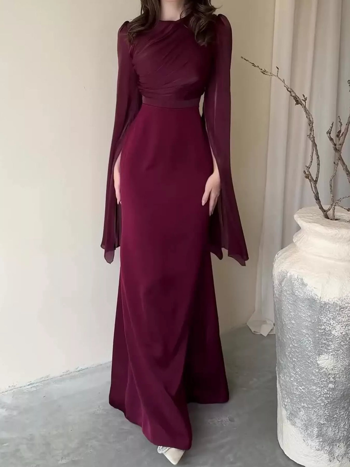 Burgundy floor-length dress with a fitted waist and flowing split sleeves