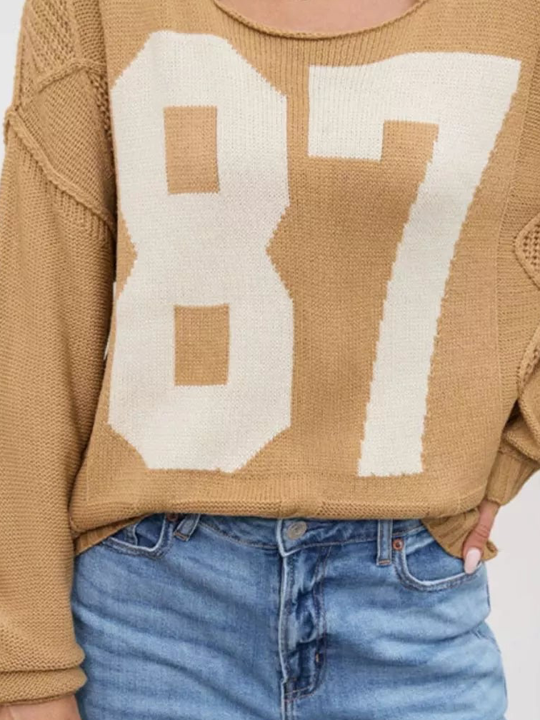 Tan cable-knit sweater with cream 87 number graphic front and ribbed cuffs