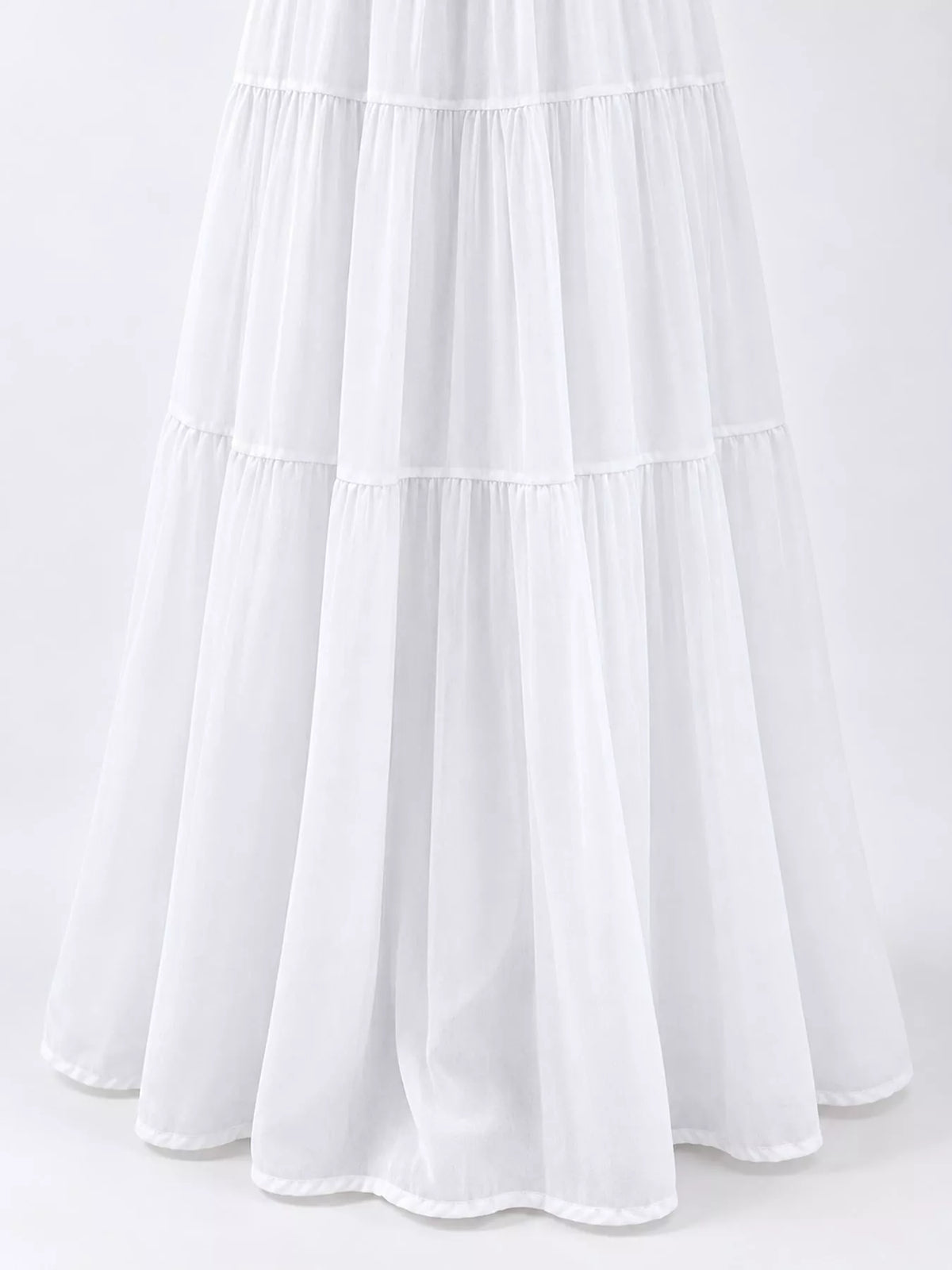 White tiered pleated maxi skirt close-up showing layered ruffles and vertical pleats