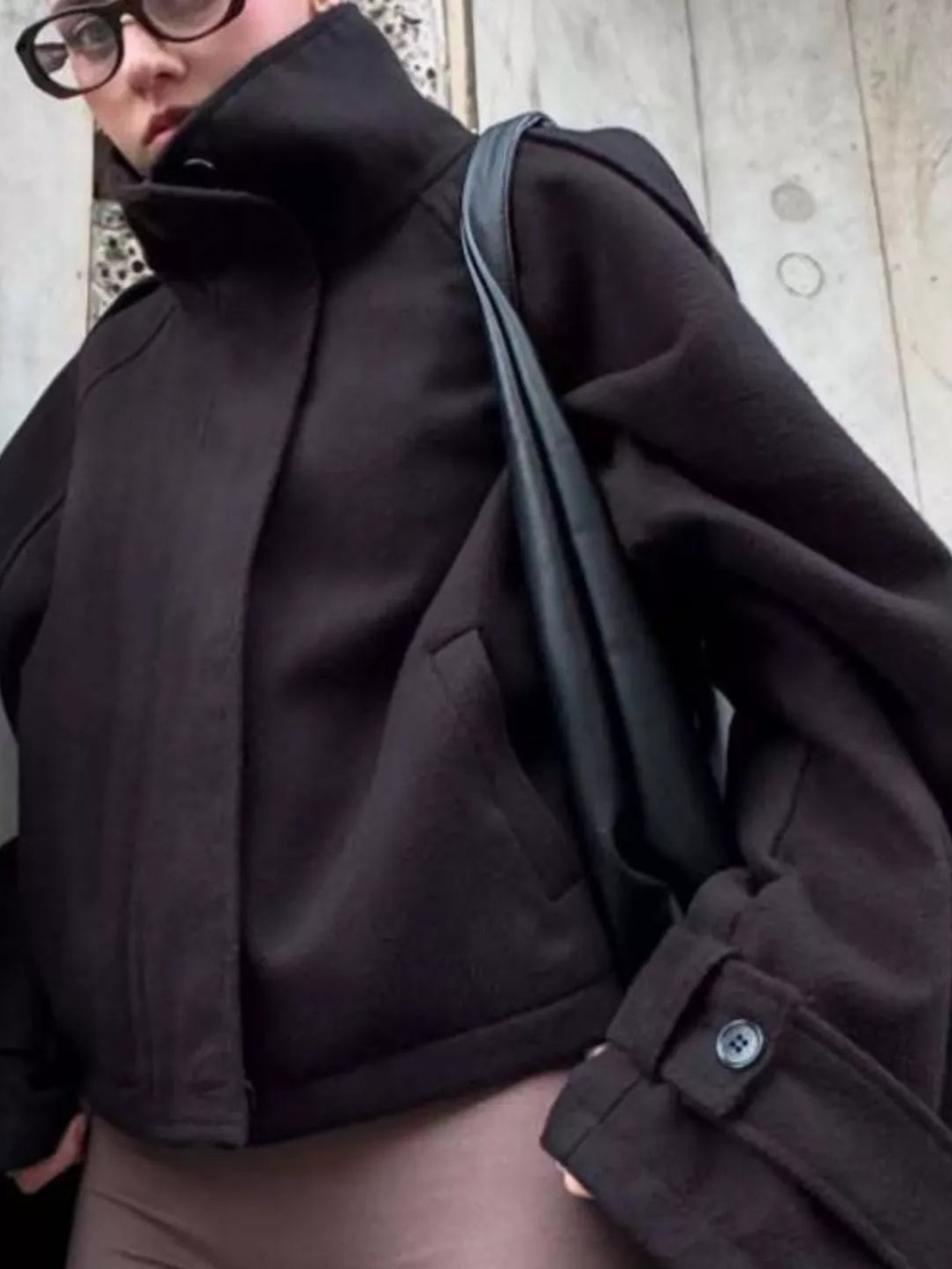 Black stand-collar zip-up jacket with sleeve tab snaps and a slanted pocket seam.