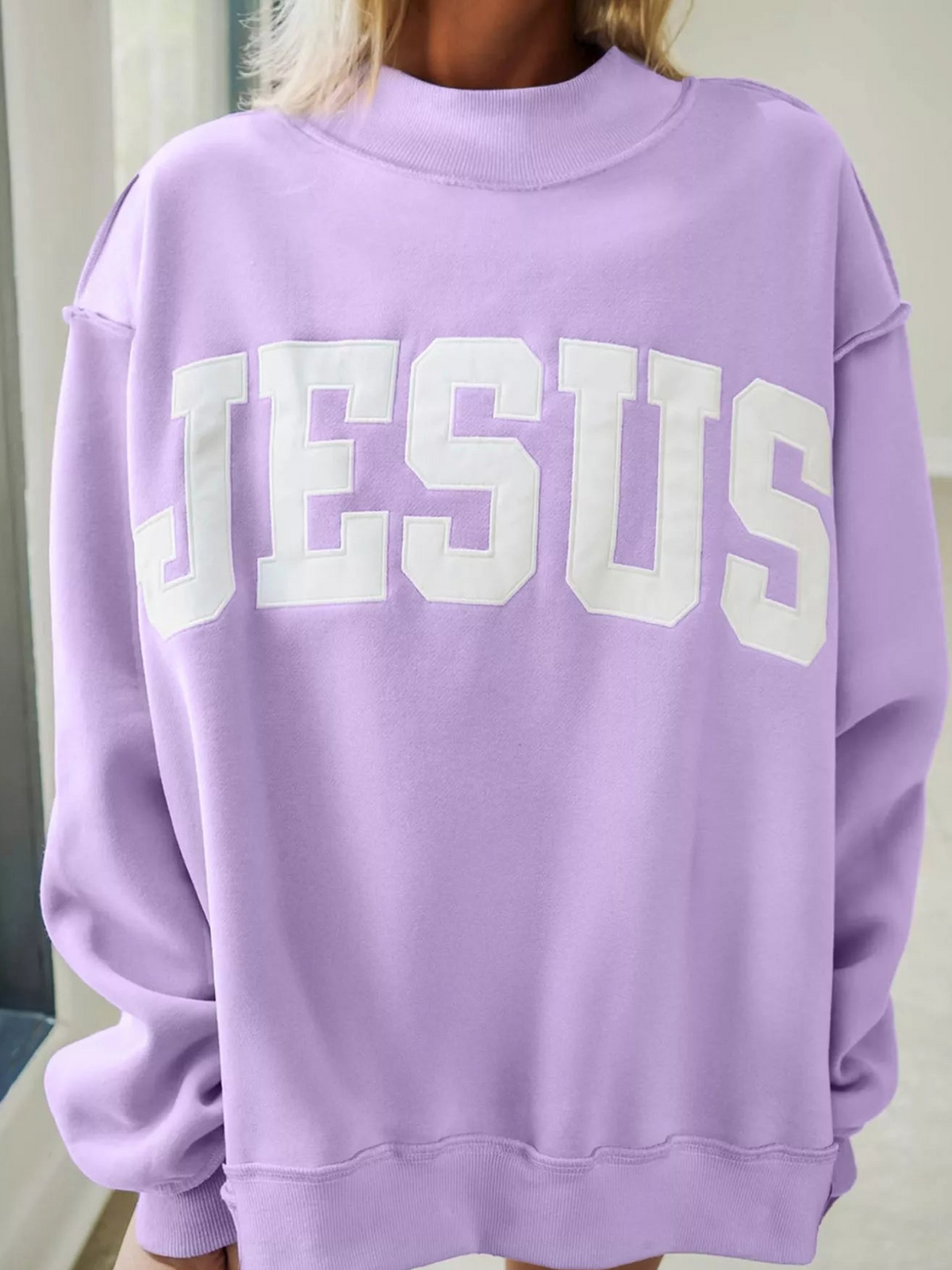 Lavender mock-neck sweatshirt with large 'JESUS' graphic across front