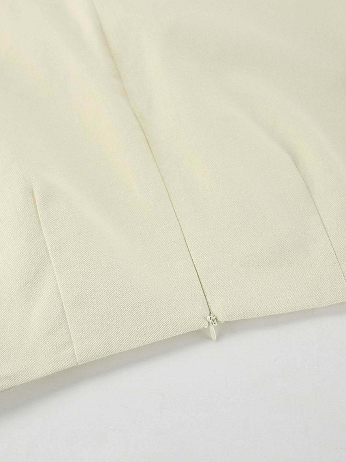 Beige skirt detail showing the side zipper and hem stitching.