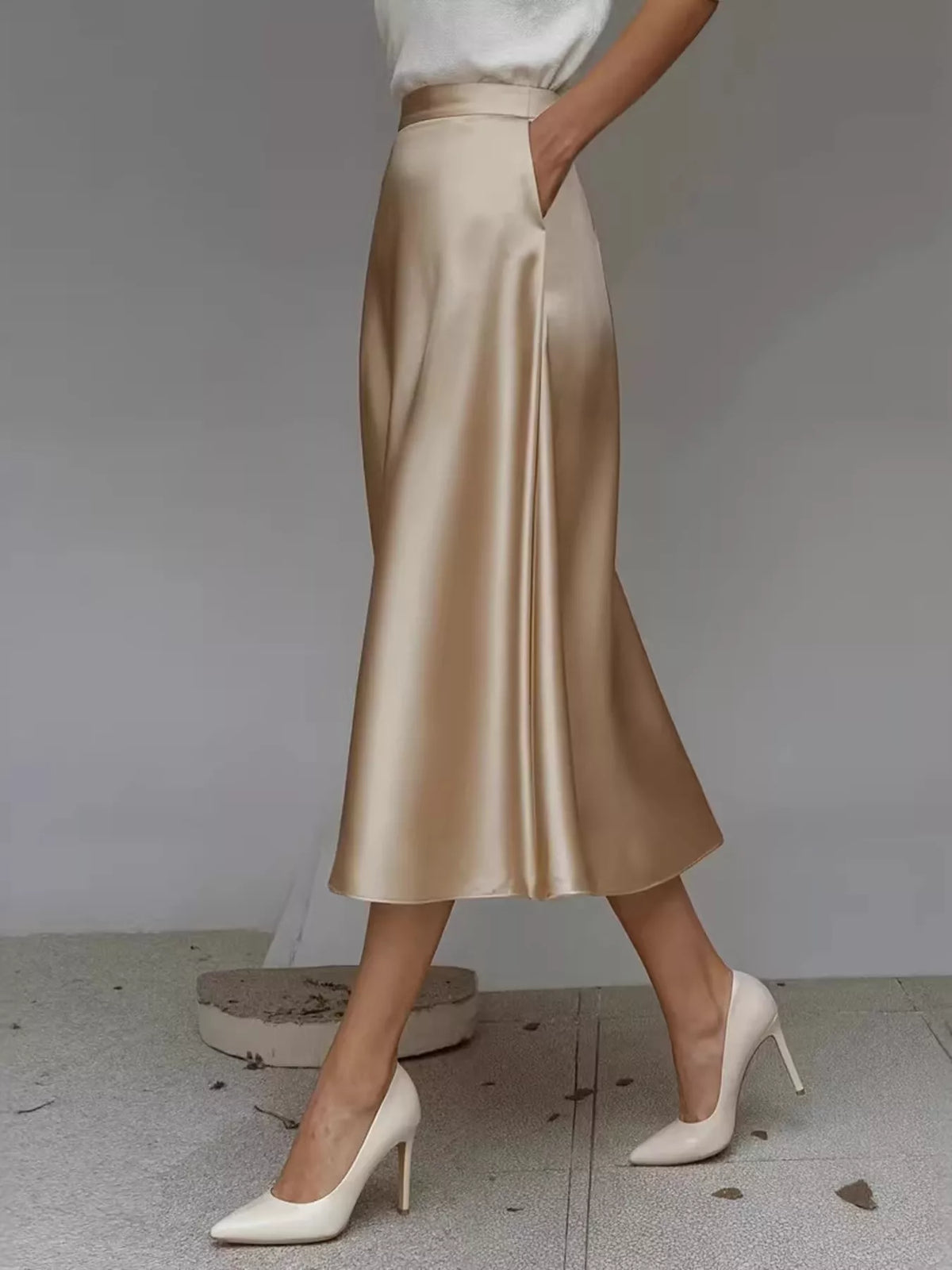 Champagne satin midi skirt with side pockets, shown at an angle