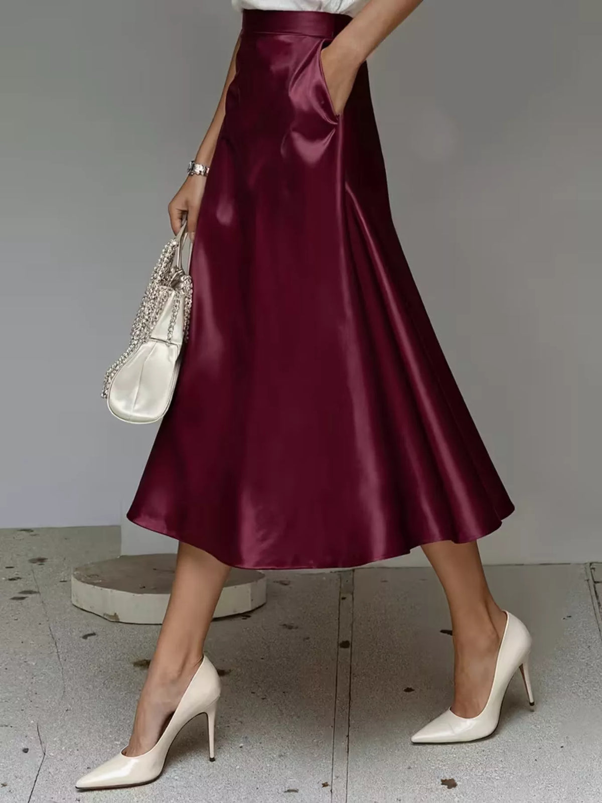 Wine red satin midi skirt with a flared hem and side pockets.