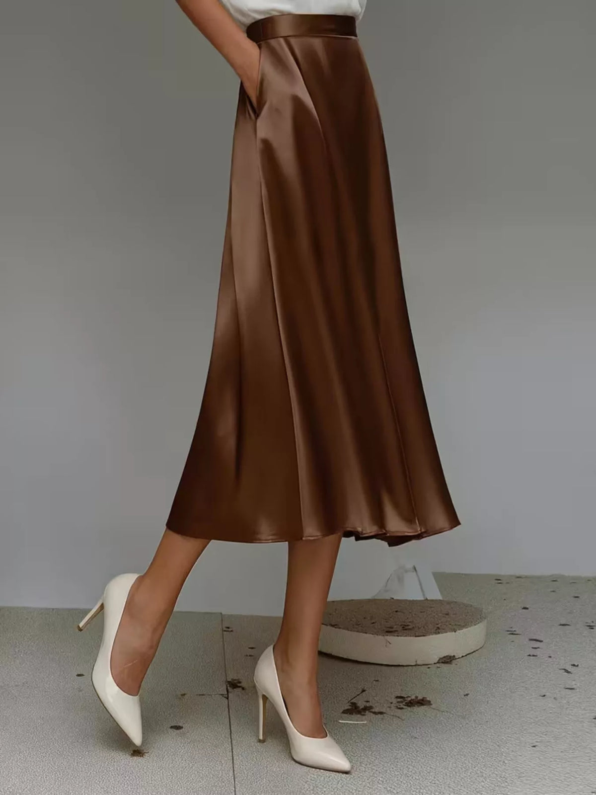 Side view of a dark brown satin midi skirt with a high waist