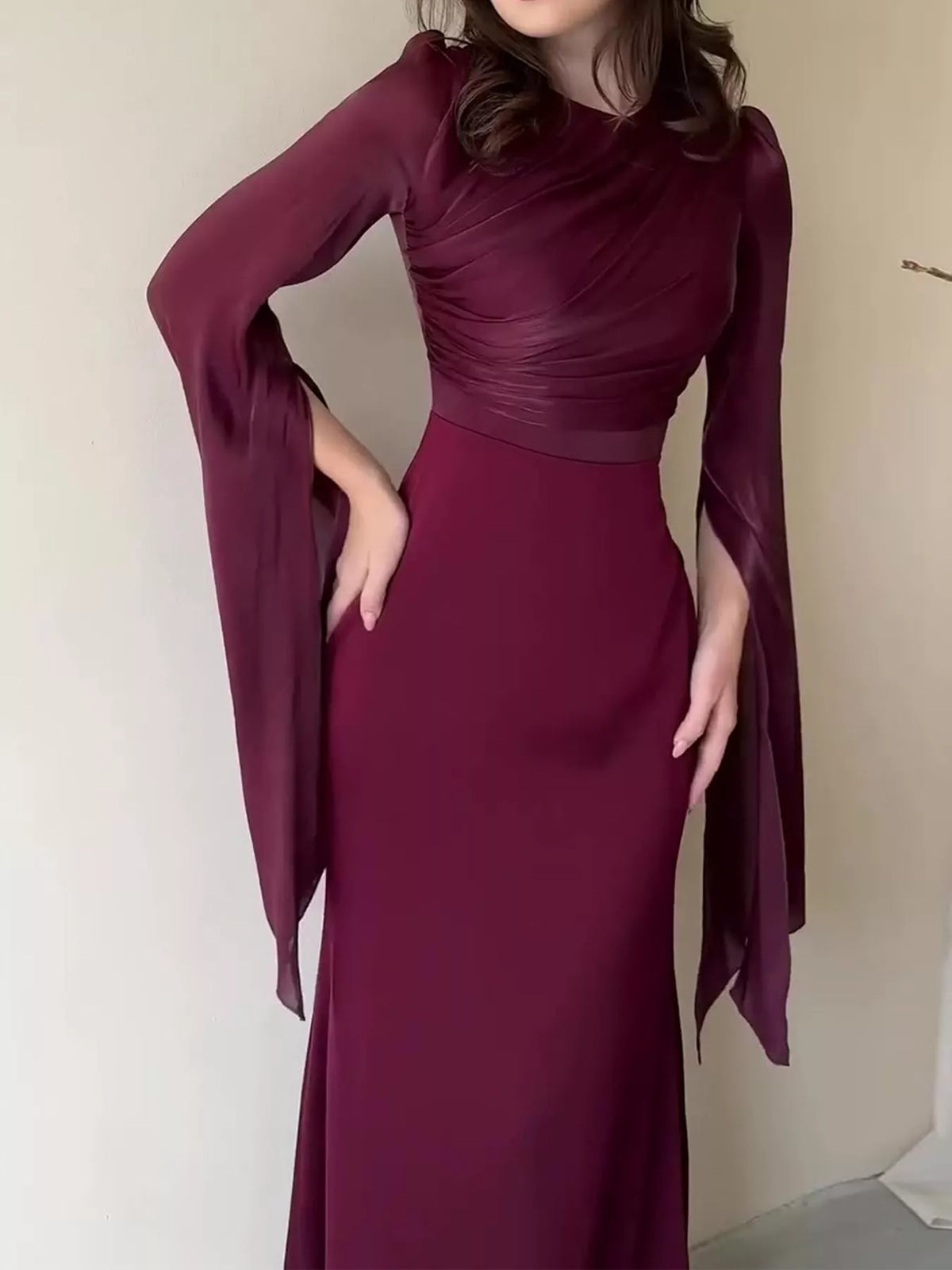 Burgundy maxi dress with a ruched bodice, fitted waist, and split flare sleeves
