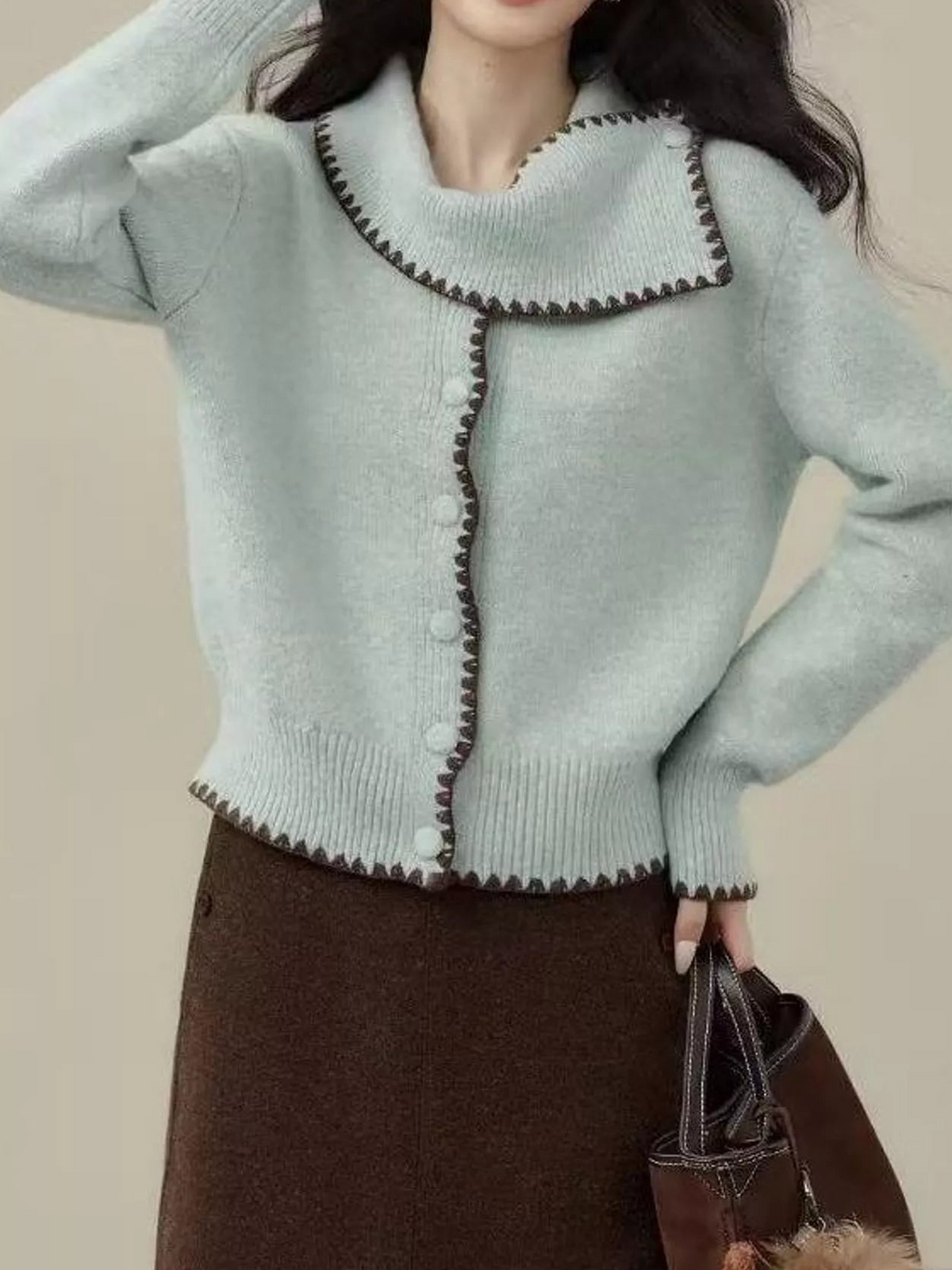 Pale blue scarf-collar cardigan with brown trim and front buttons, shown with a ribbed hem