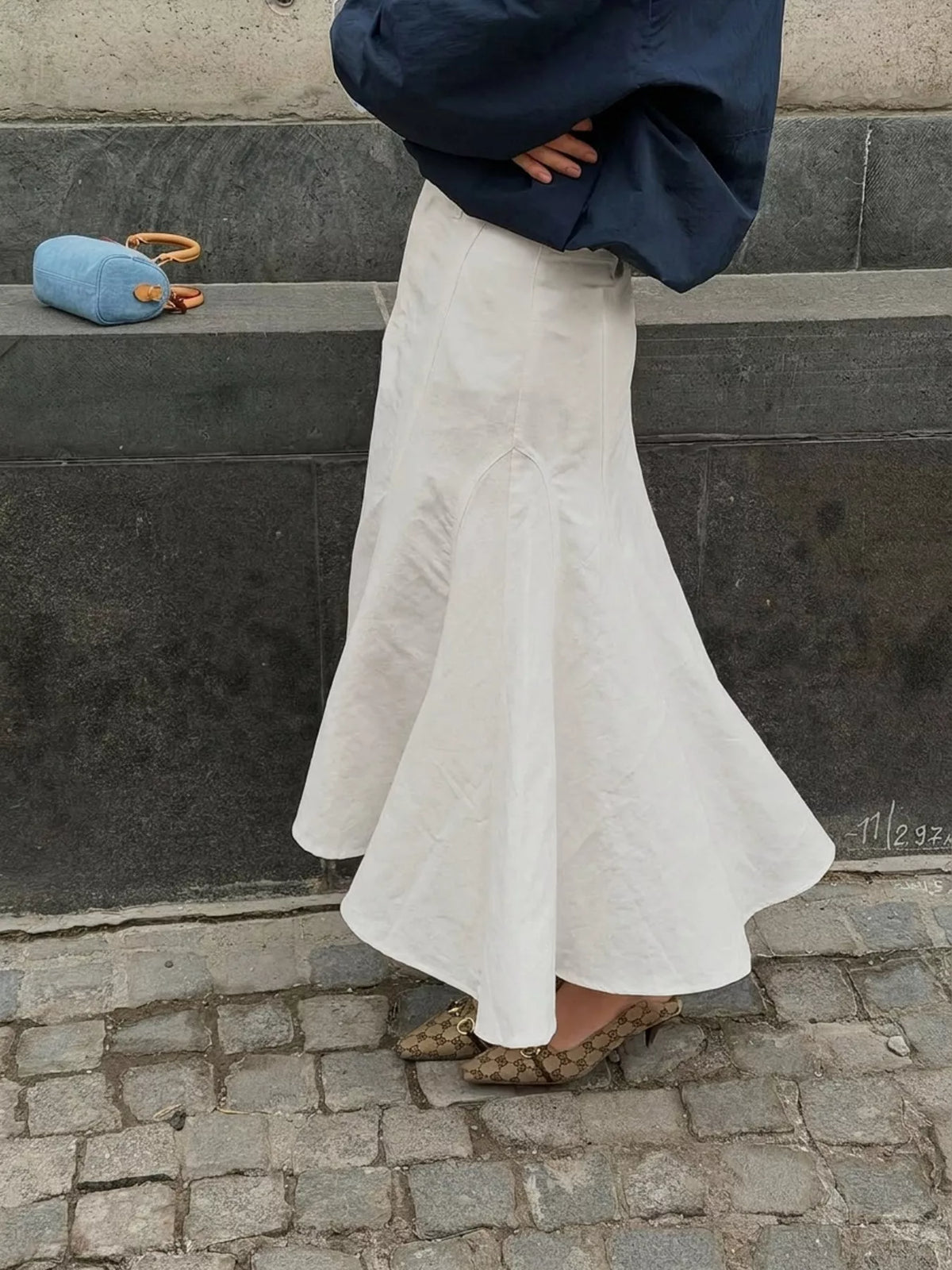 White high-waisted mermaid midi skirt shown from the side with a flared hem