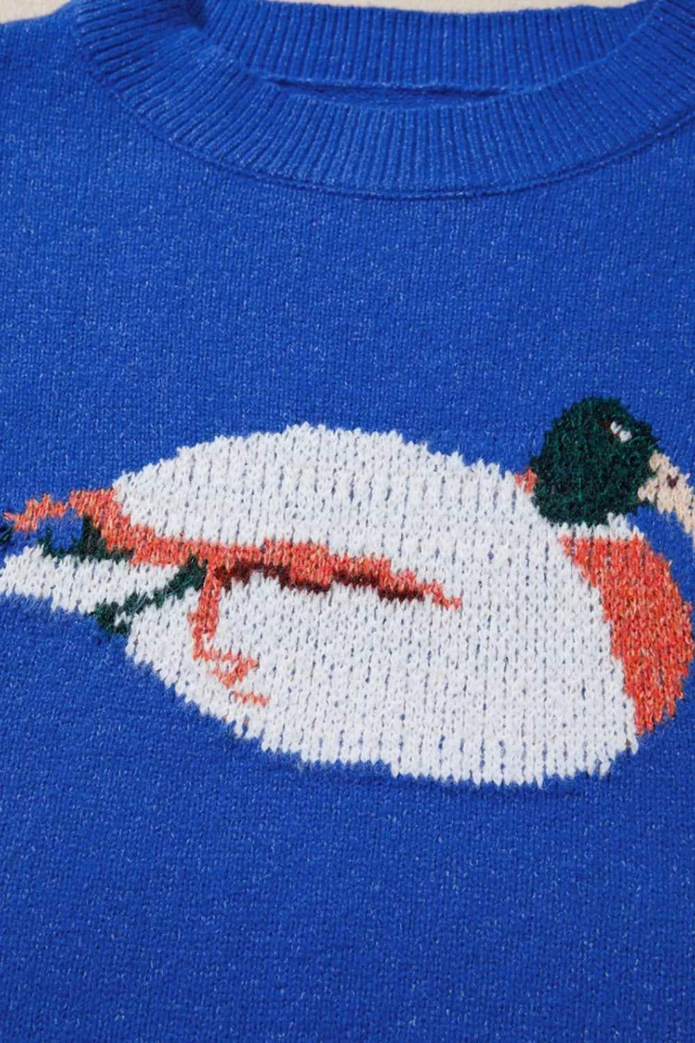 Royal blue sweater close-up of white duck graphic with orange and green accents