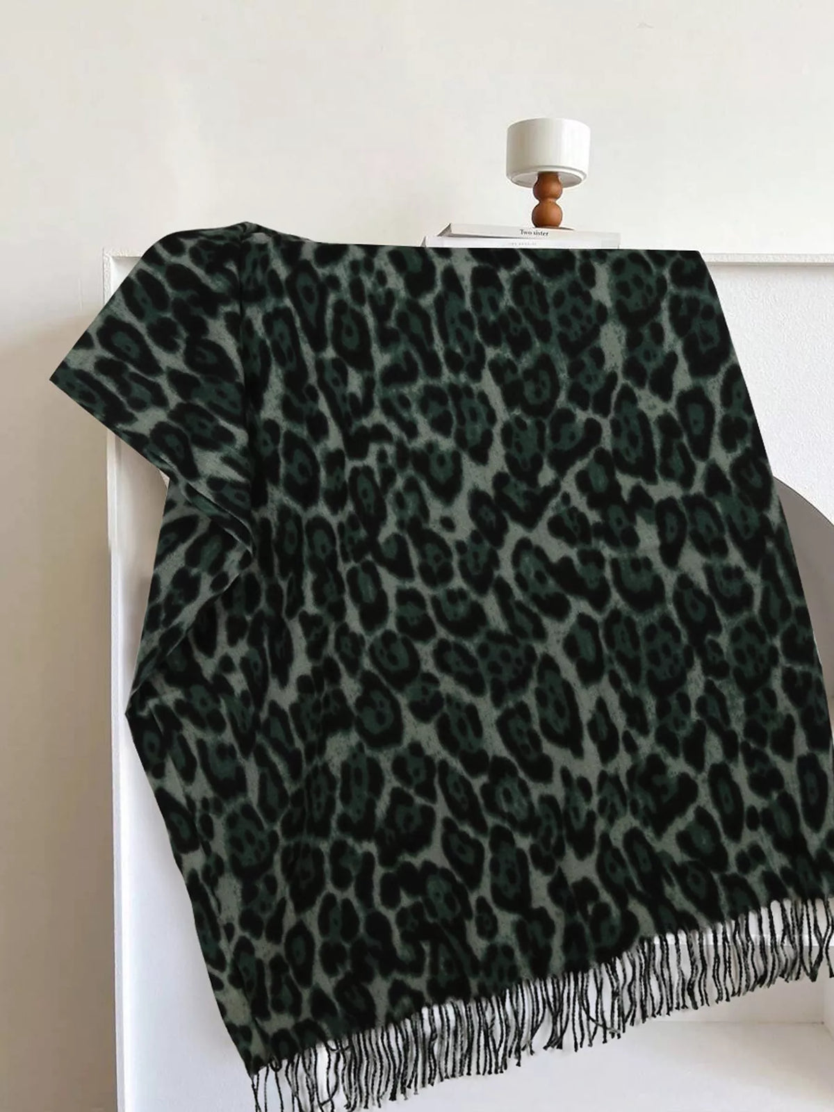 Leopard print fringe scarf in deep green with darker spots and soft drape.