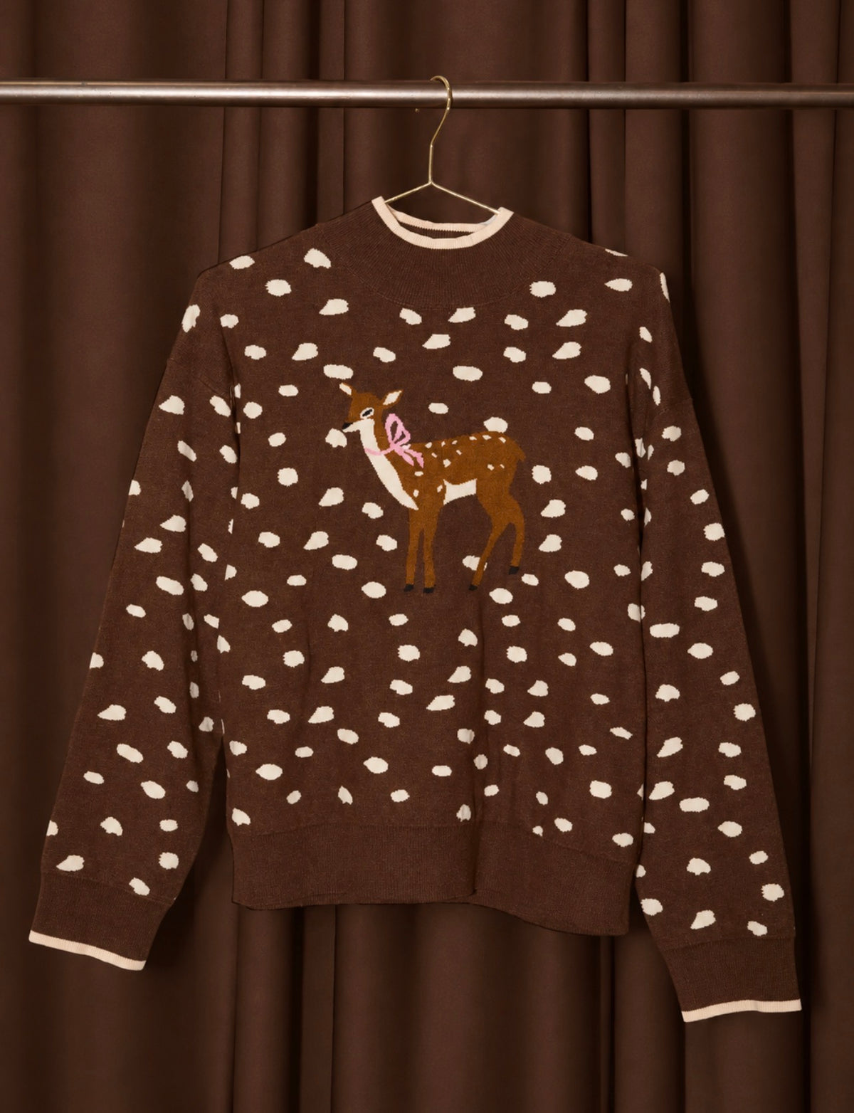 Hanging dark brown mock-neck sweater with white dots and deer graphic