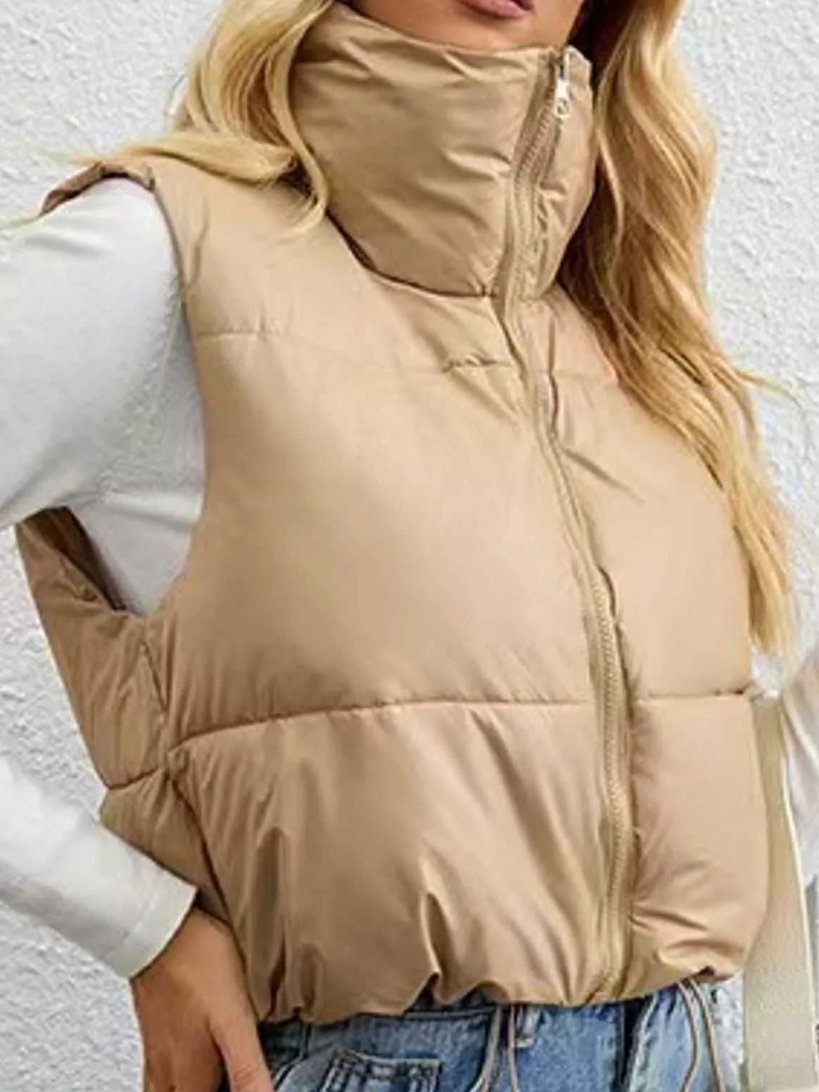 Beige zip-up puffer vest with stand collar and quilted panels, sleeveless design