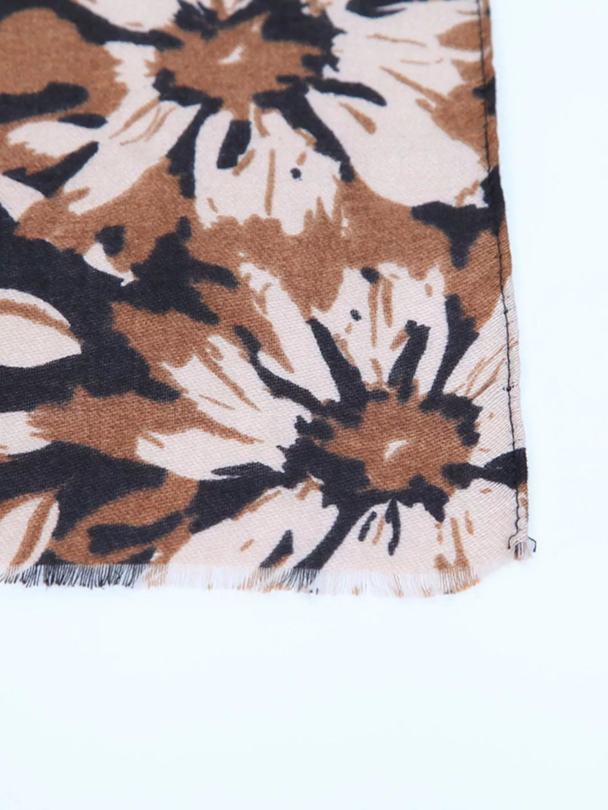 Floral scarf close-up: tan, cream, and dark flower pattern with fringed edge