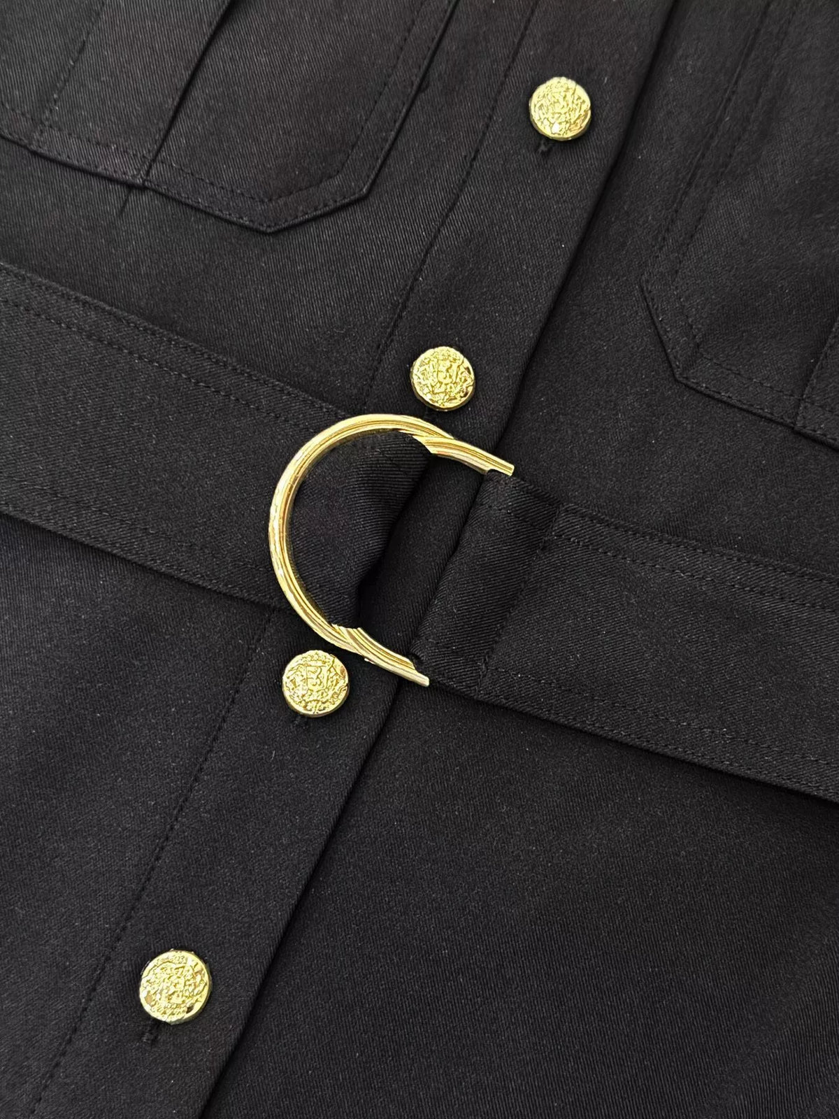 Black dress front detail with gold buttons and circular belt buckle ring