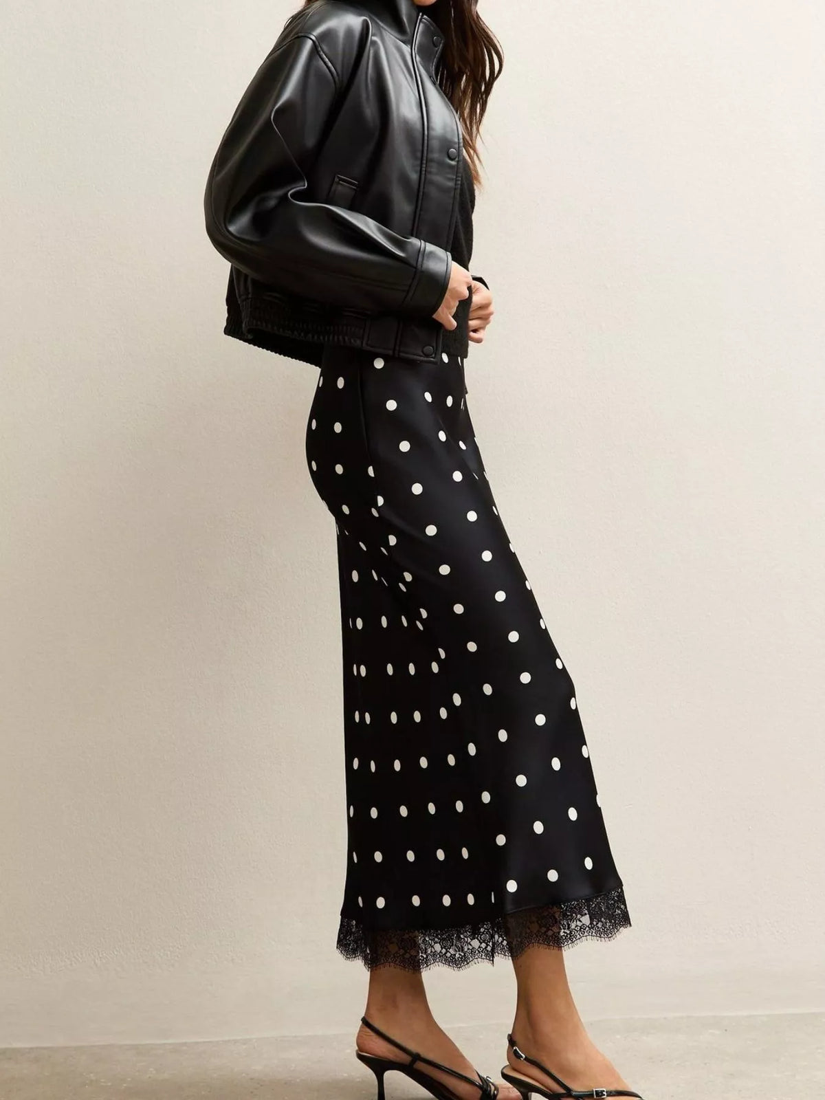Black midi skirt with white polka dots and lace hem, shown in a side view.