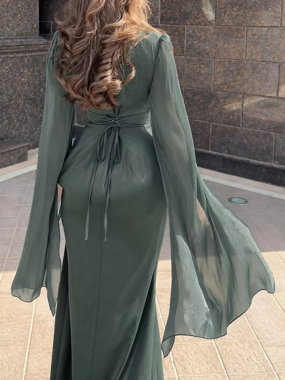 Back of dark gray maxi dress with a tied waist and flowing sheer sleeves