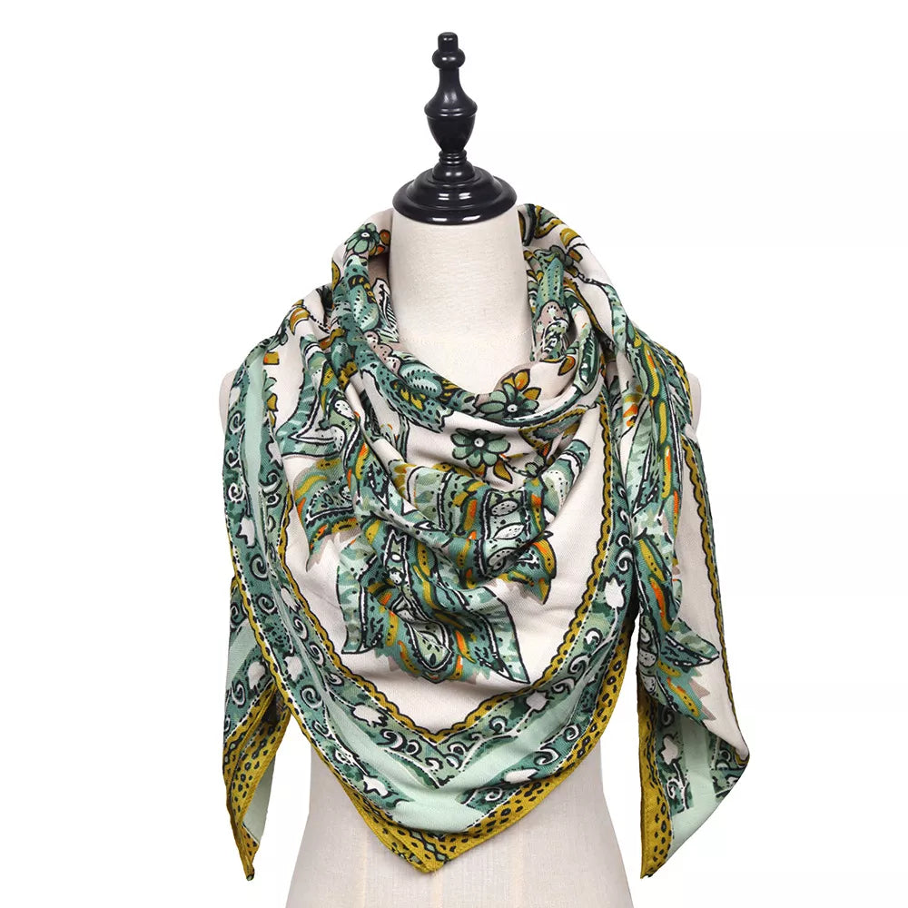 Square silk-feel scarf draped on a mannequin, with a green, yellow and ivory paisley print.