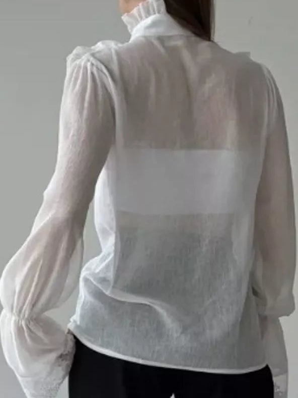 Back view of a white sheer shirt with a high ruffled collar and gathered sleeves