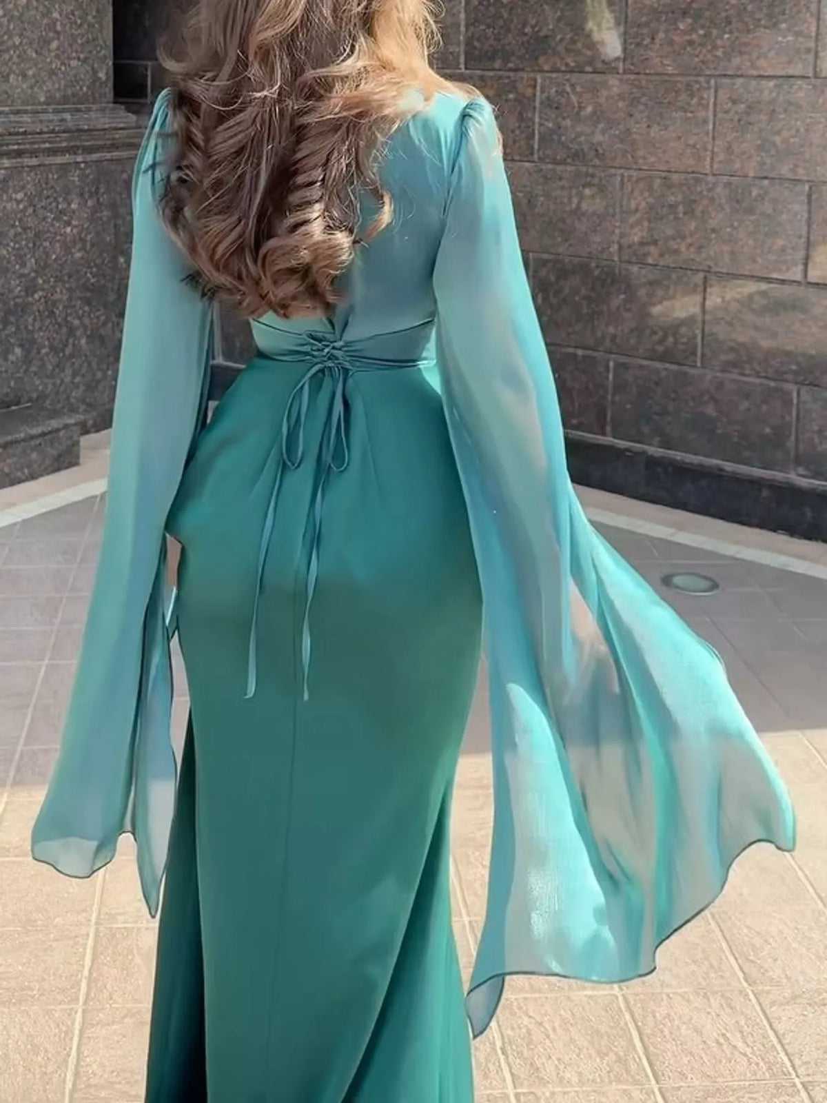 Back of teal maxi dress with a tied waist and sheer flared sleeves